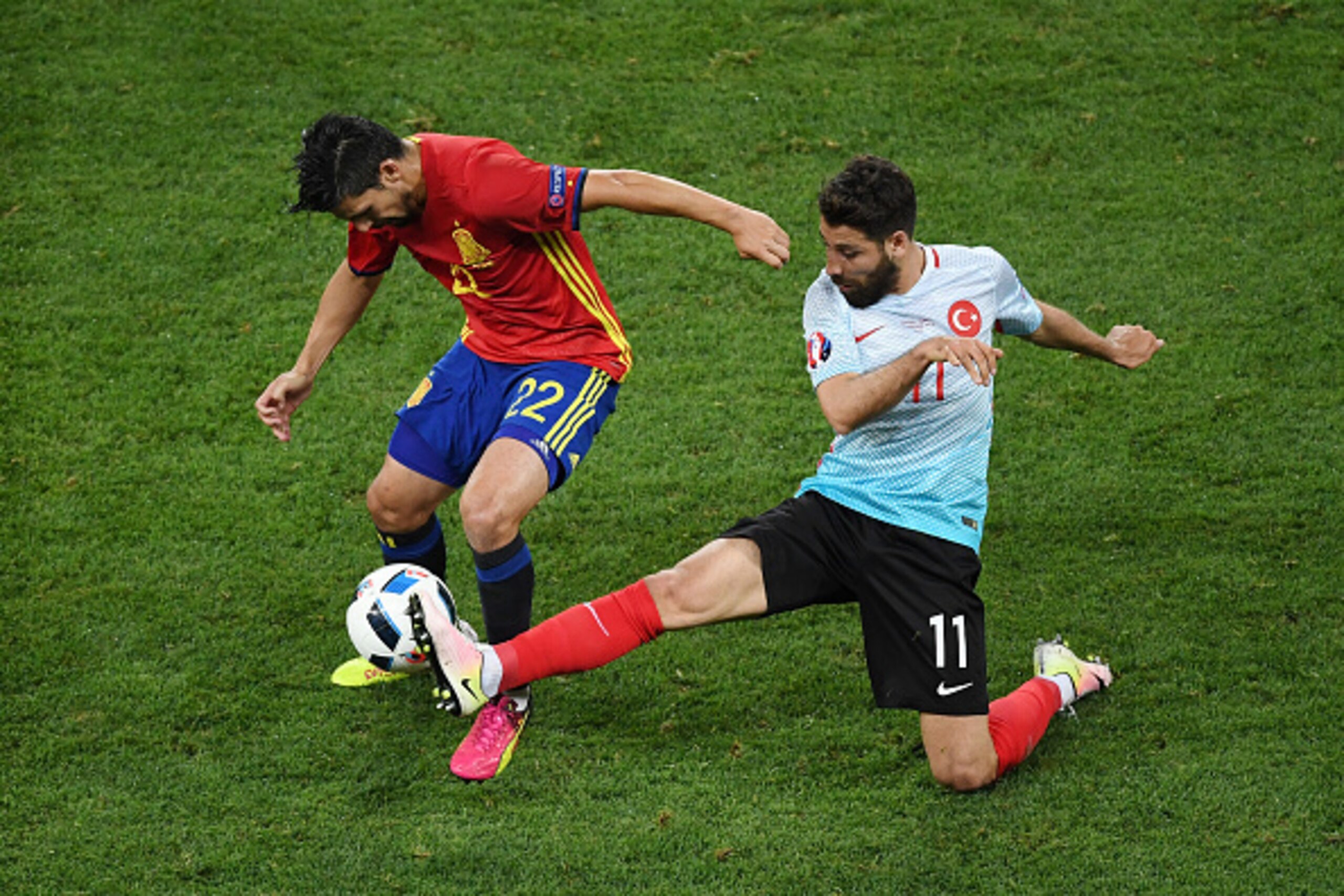 NICE, FRANCE - JUNE 17: Olcay Sahan of Turkey tackles Nolito of Spain during the UEFA EURO 2016 Group D match between Spain and Turkey at Allianz Riviera Stadium on June 17, 2016 in Nice, France.  (Photo by Laurence Griffiths/Getty Images)