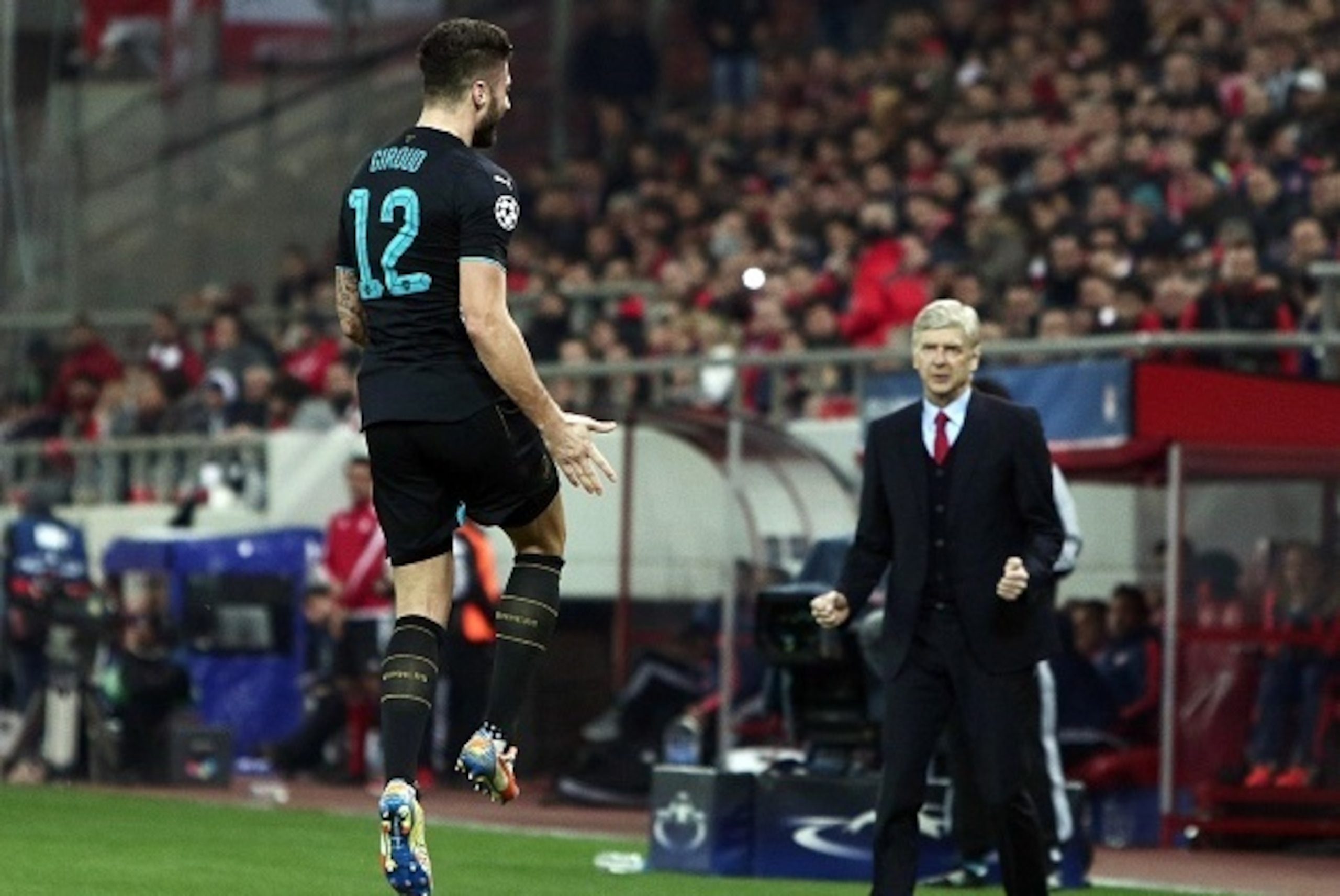 TOPSHOT - Arsenal's French forward Olivier Giroud (L) celebrates scoring 0-3 with Arsenal's French Coach Arsene Wenger during the UEFA Champions League Group F football match between Olympiacos and Arsenal at the Georgios Karaiskakis Stadium in Piraeus ne