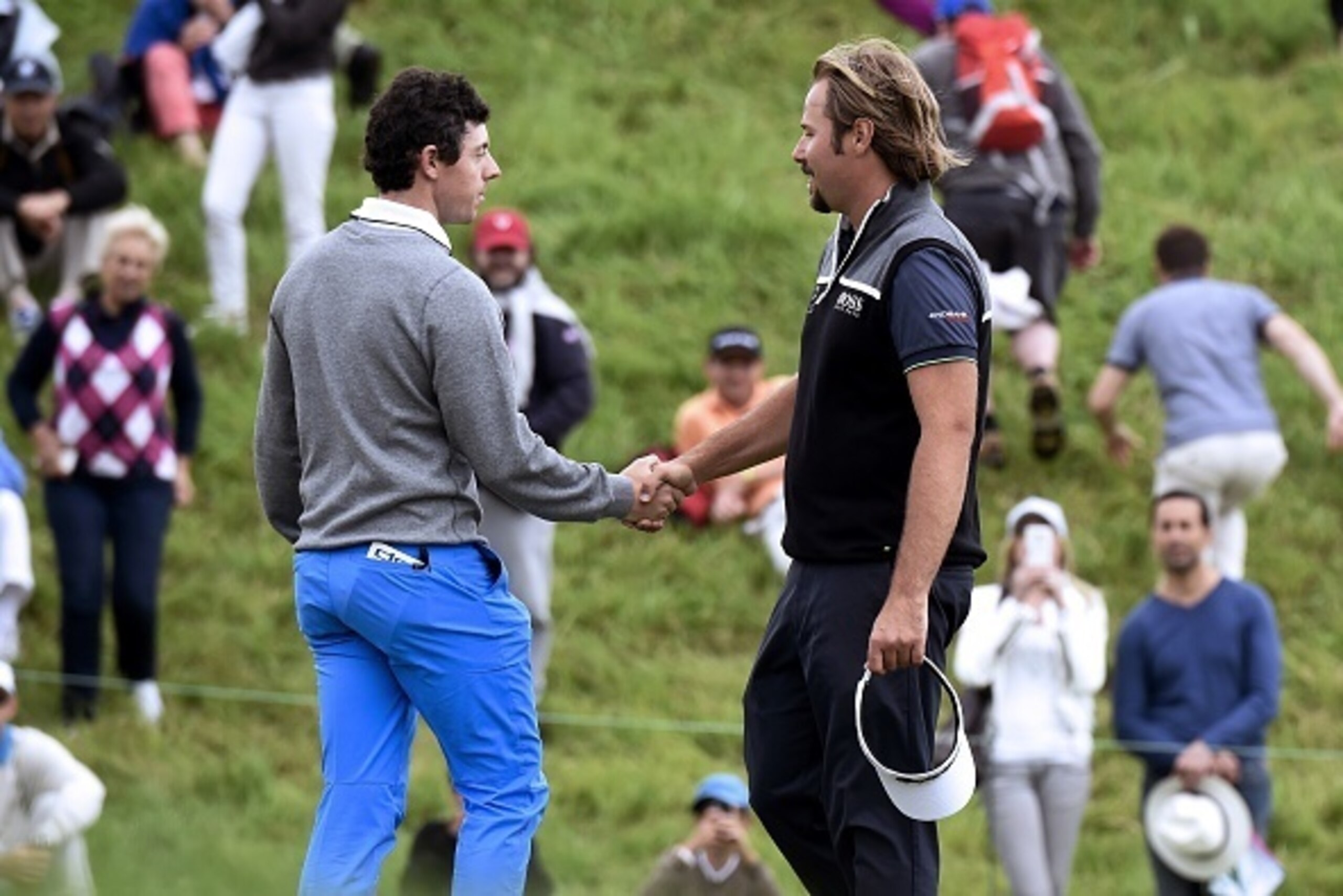 Northern Ireland's Rory McIlroy (L) shakes hands with France's Victor Dubuisson (R) on the 9th green during the first round of the 100th French Golf Open on July 30, 2016 at Le Golf National in Guyancourt, near Paris. / AFP / DOMINIQUE FAGET        (Photo