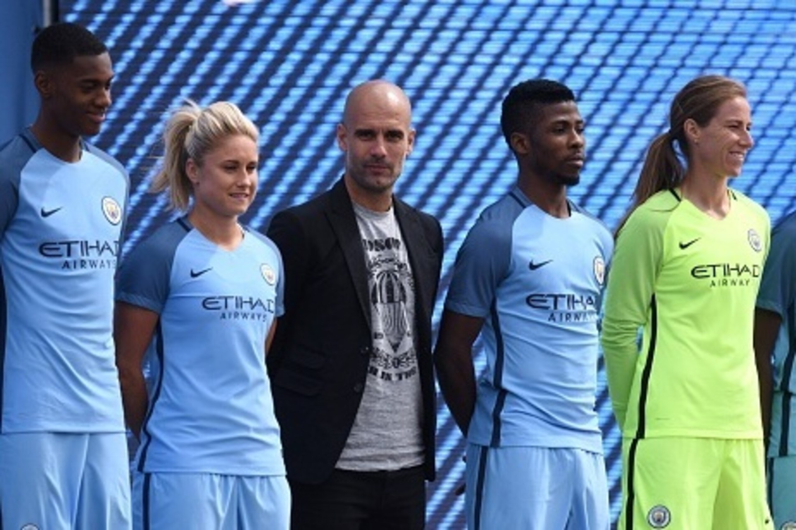 Spanish football coach Pep Guardiola (C) stands with players from various Manchester City squads as he is officially unveiled as the club's new manager at the City Football Academy in Manchester, north west England on July 3, 2016. / AFP / OLI SCARFF     