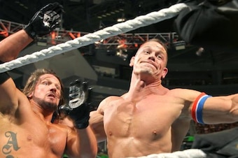 John Cena looks to smash AJ Styles into the turnbuckle.