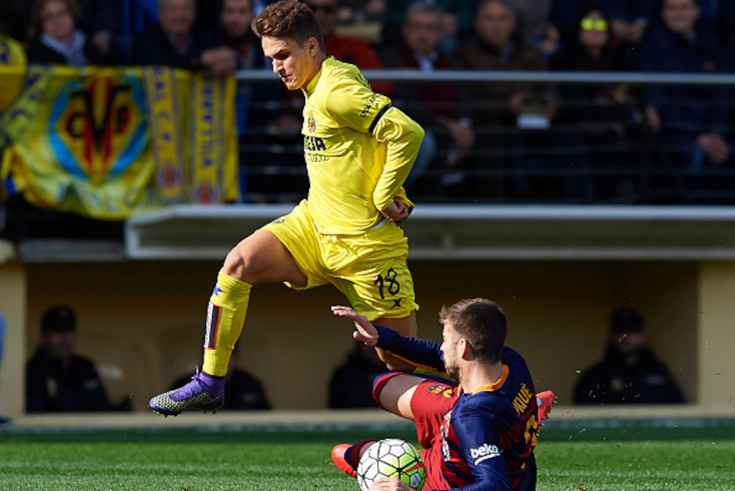 VILLARREAL, SPAIN - MARCH 20:  Denis Suarez (18) of Villarreal is tackled by Gerard Pique of Barcelona during the La Liga match between Villarreal CF and FC Barcelona at El Madrigal on March 20, 2016 in Villarreal, Spain.  (Photo by Manuel Queimadelos Alo