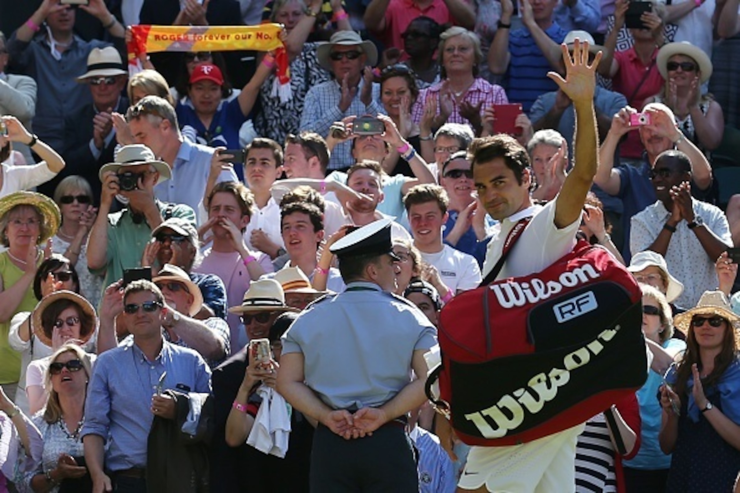 Switzerland's Roger Federer waves as he leaves the court after beating Croatia's Marin Cilic during their men's singles quarter-final match on the tenth day of the 2016 Wimbledon Championships at The All England Lawn Tennis Club in Wimbledon, southwest Lo