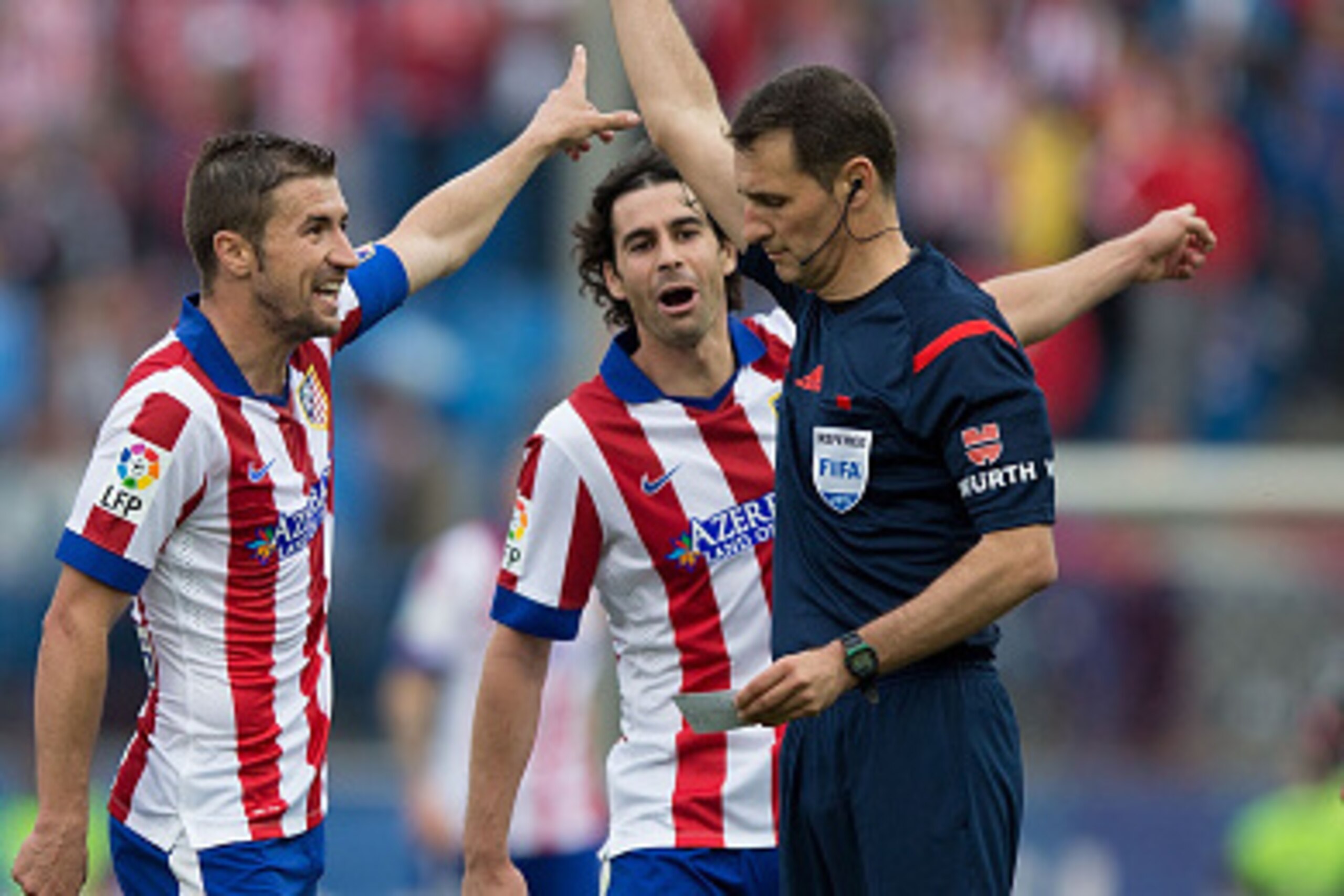 MADRID, SPAIN - APRIL 25: referee Clos Gomez (R) shiws the yellow card to Gabi Fernandez (2ndL) as his teammates Diego Godin (L) and Tiago Mendes (2ndR) protest during the La Liga match between Club Atletico de Madrid and Elche FC at Vicente Calderon Stad