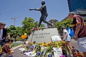 SAN DIEGO, CA - JUNE 16:  Carina Arrendondo (R), 12, accompanied by her father Mario Arrendondo, places a sign of tribute to the late San Diego Padres great Tony Gwynn at the base of a statue of Gwynn at Petco Park where the Padres play June 16, 2014 in S