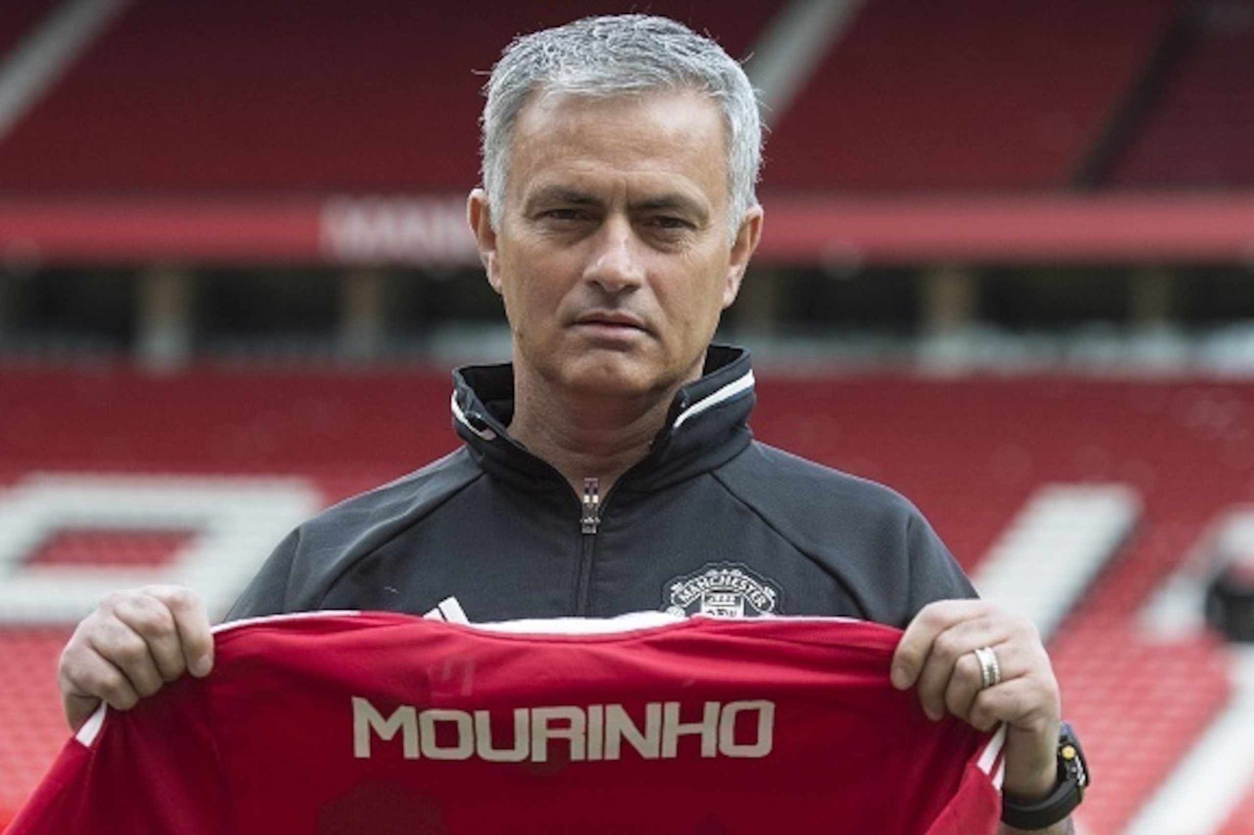 Manchester United's new Portuguese manager Jose Mourinho poses with a scarf on the pitch during a photocall at Old Trafford stadium in Manchester, northern England, on July 5, 2016.
Jose Mourinho officially started work as Manchester United manager at the