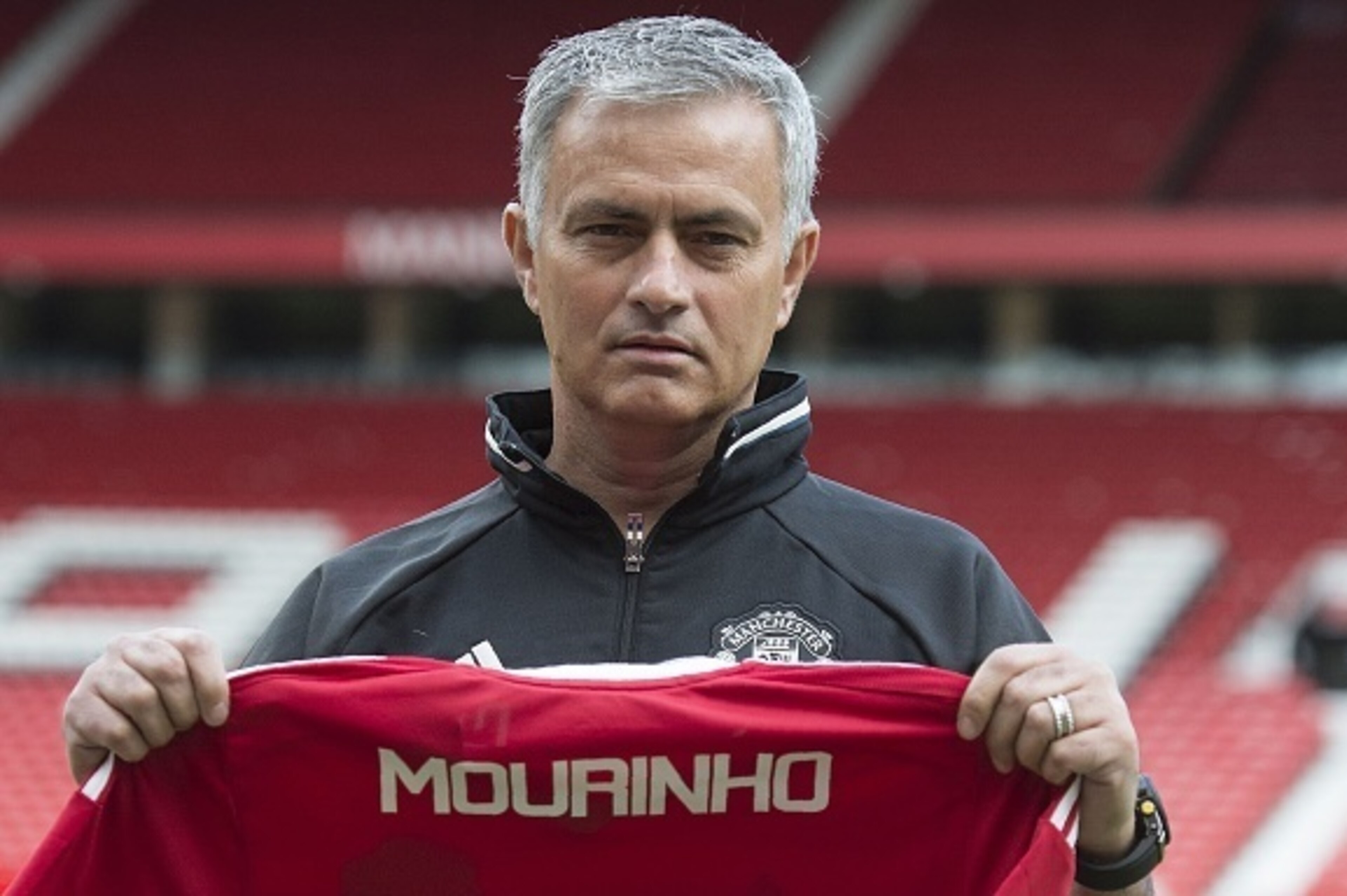 Manchester United's new Portuguese manager Jose Mourinho poses with a scarf on the pitch during a photocall at Old Trafford stadium in Manchester, northern England, on July 5, 2016.
Jose Mourinho officially started work as Manchester United manager at the