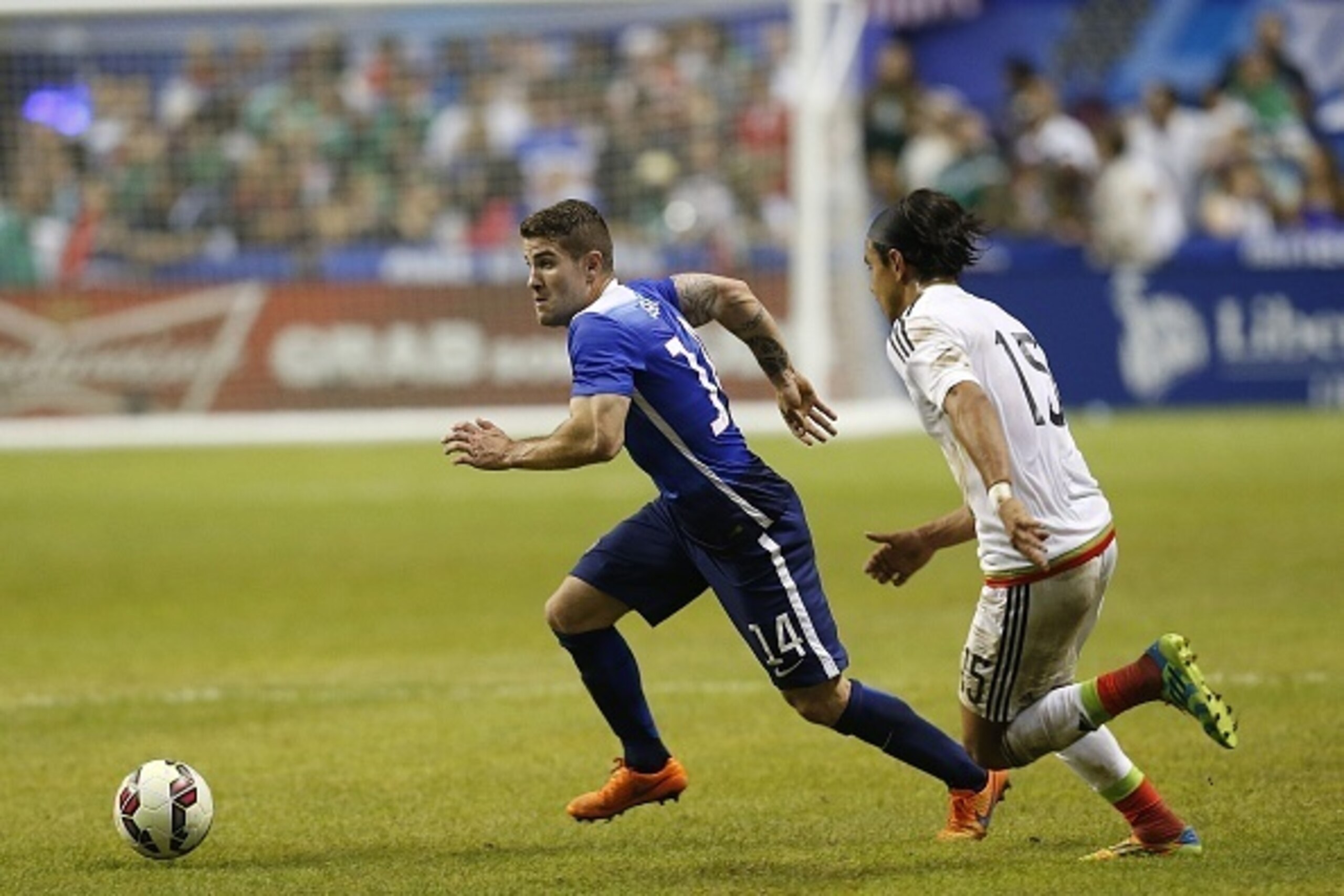 SAN ANTONIO, TX - APRIL 15:  Greg Garza #14 of the United States outruns Gerardo Flores #15 of Mexico for the ball during an international friendly match at the Alamodome on April 15, 2015 in San Antonio, Texas.  (Photo by Chris Covatta/Getty Images)