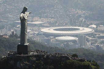 RIO DE JANEIRO, BRAZIL - JULY 04:  Visitors gather beneath the Christ the Redeemer statue as Maracana stadium, site of the Olympic opening ceremonies, stands in the background on July 4, 2016 in Rio de Janeiro, Brazil. July 5 marks the one-month mark to t
