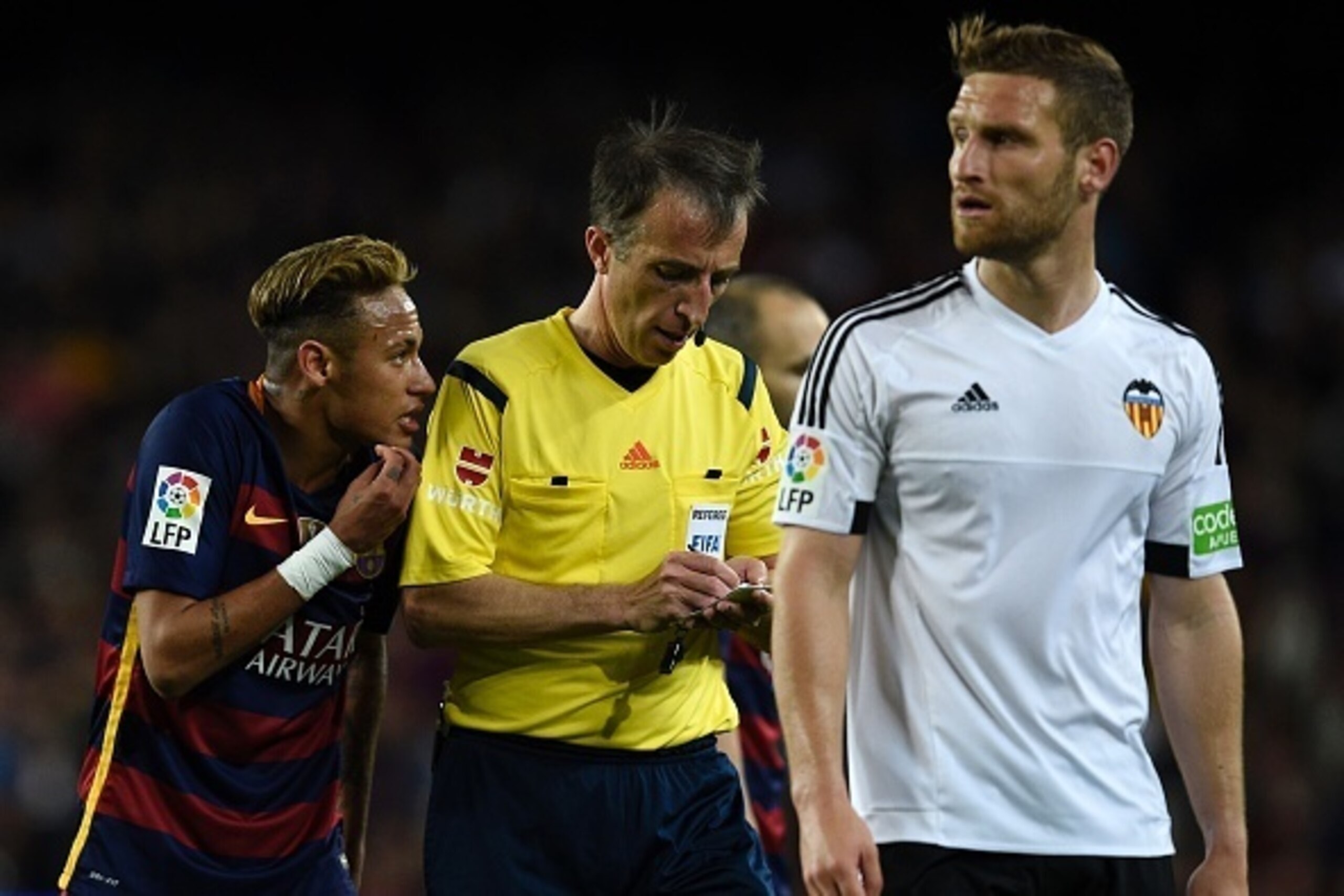 Barcelona's Brazilian forward Neymar (L) argues with the referee as Valencia's German defender Shkodran Mustafi looks across during the Spanish league football match FC Barcelona vs Valencia CF at the Camp Nou stadium in Barcelona on April 17, 2016. / AFP