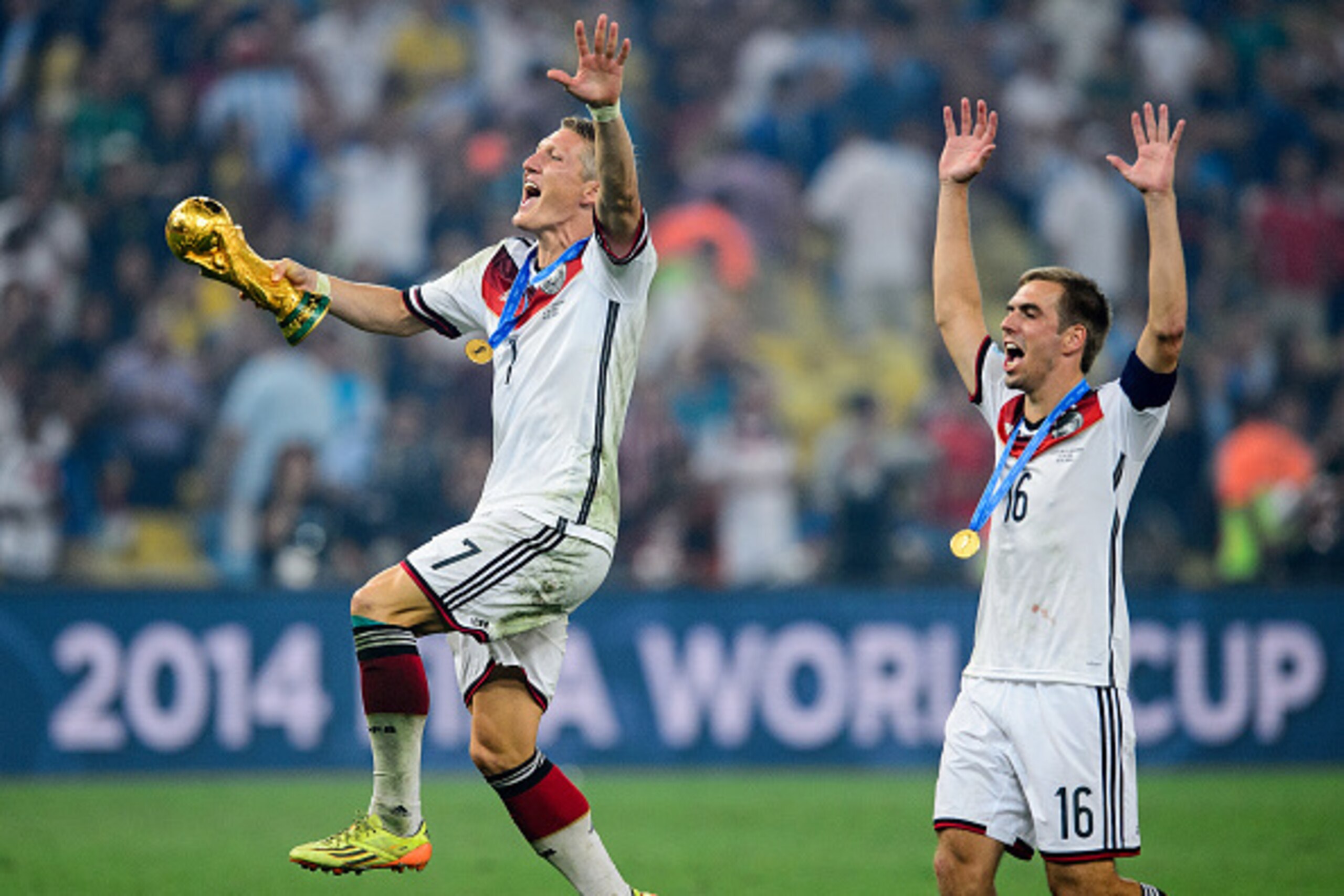 RIO DE JANEIRO, BRAZIL - JULY 13:   Bastian Schweinsteiger (L) of Germany and Philipp Lahm (R)  of Germany celebrate with the World Cup trophy after defeating Argentina 1-0 in extra time during the 2014 FIFA World Cup Brazil Final match between Germany an
