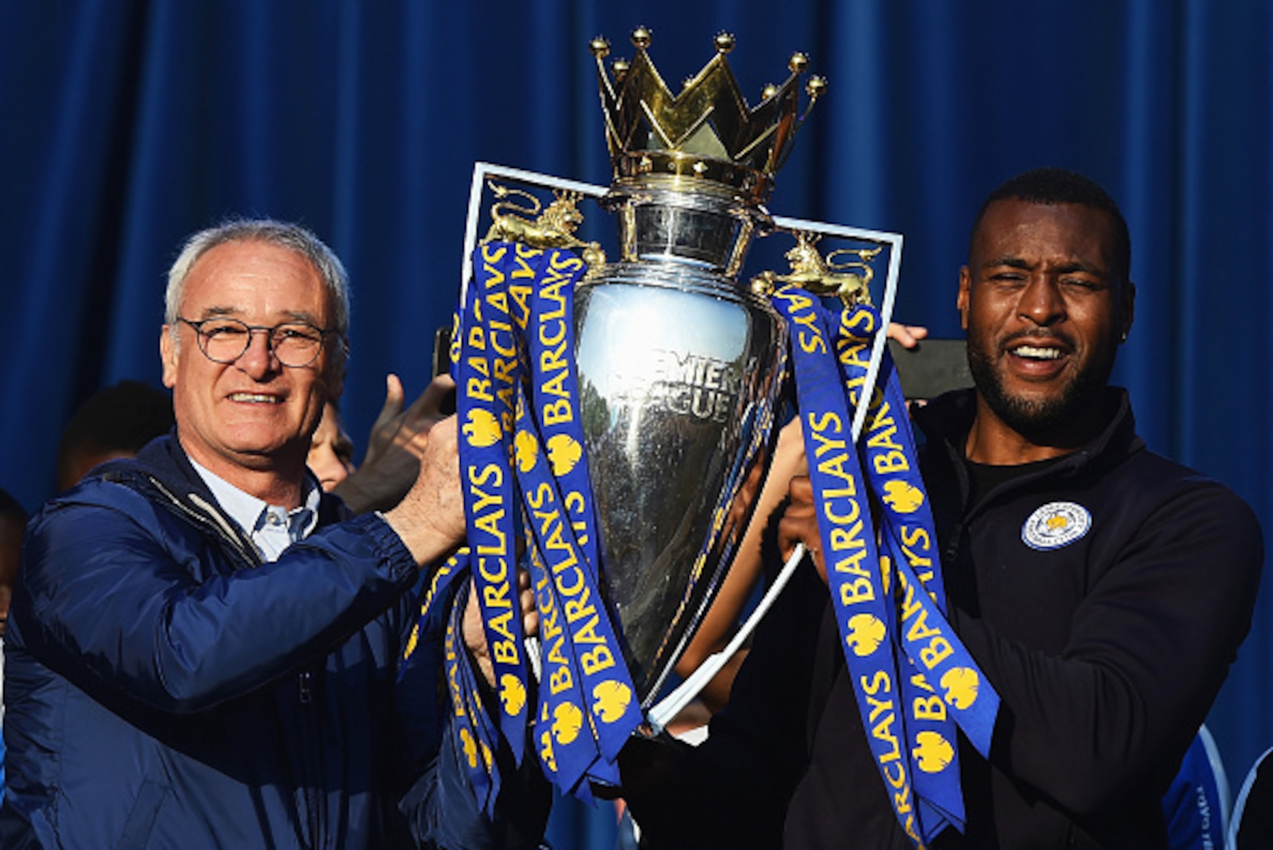 LEICESTER, ENGLAND - MAY 16:  (L-R) Claudio Ranieri Manager of Leicester City and captain Wes Morgan of Leicester City show the trophy to the fans during the Leicester City Barclays Premier League winners bus parade on May 16, 2016 in Leicester, England. 