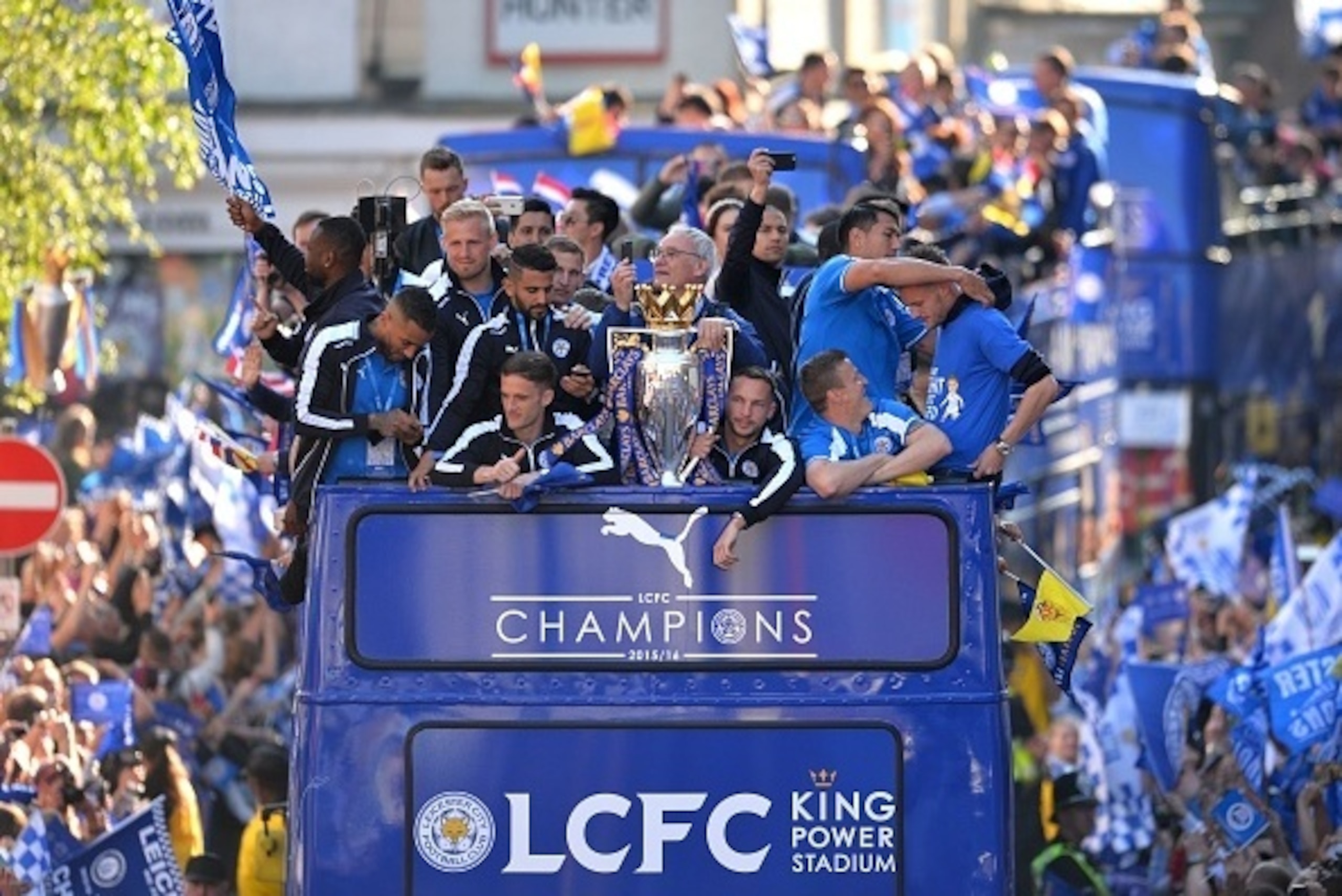 Leicester City's Italian manager Claudio Ranieri (C) stands with the Premier league trophy as the Leicester City team take part in an open-top bus parade through Leicester to celebrate winning the Premier League title on May 16, 2016.

 / AFP / GLYN KIRK 