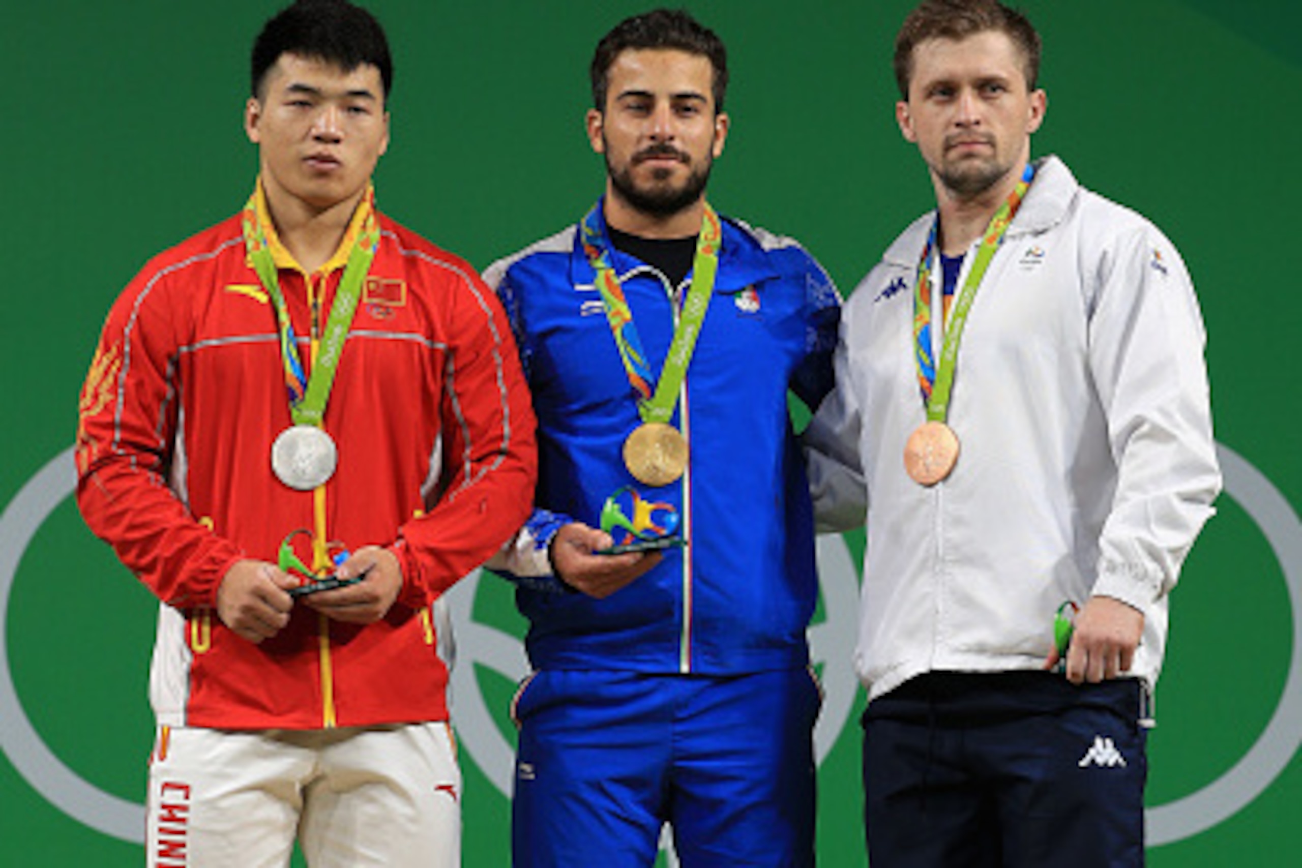 RIO DE JANEIRO, BRAZIL - AUGUST 12:  Silver medalist Tao Tian of China, gold medalist Rostami Kianoush of Iran and bronze medalist Gabriel Sincraian of Roumania stand on the podium during the medal ceremony for the Weightlifting - Men's 85kg on Day 7 of t