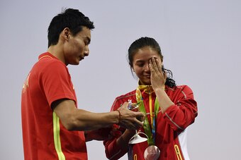 Silver medallist China's He Zi (R), reacts she receives a marriage proposal from Chinese diver Qin Kai during the podium ceremony of the Women's diving 3m Springboard Final at the Rio 2016 Olympic Games at the Maria Lenk Aquatics Stadium in Rio de Janeiro