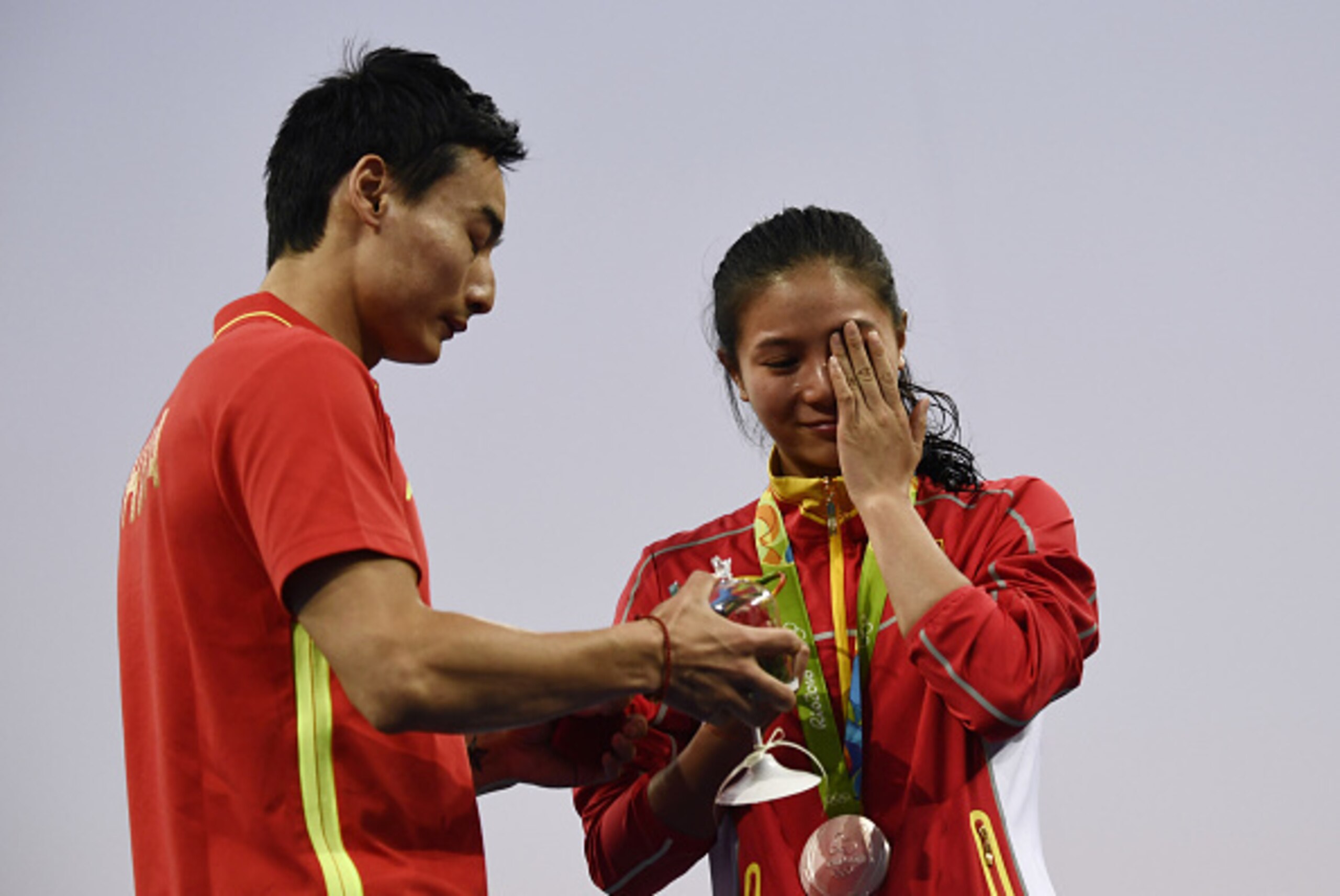 Silver medallist China's He Zi (R), reacts she receives a marriage proposal from Chinese diver Qin Kai during the podium ceremony of the Women's diving 3m Springboard Final at the Rio 2016 Olympic Games at the Maria Lenk Aquatics Stadium in Rio de Janeiro