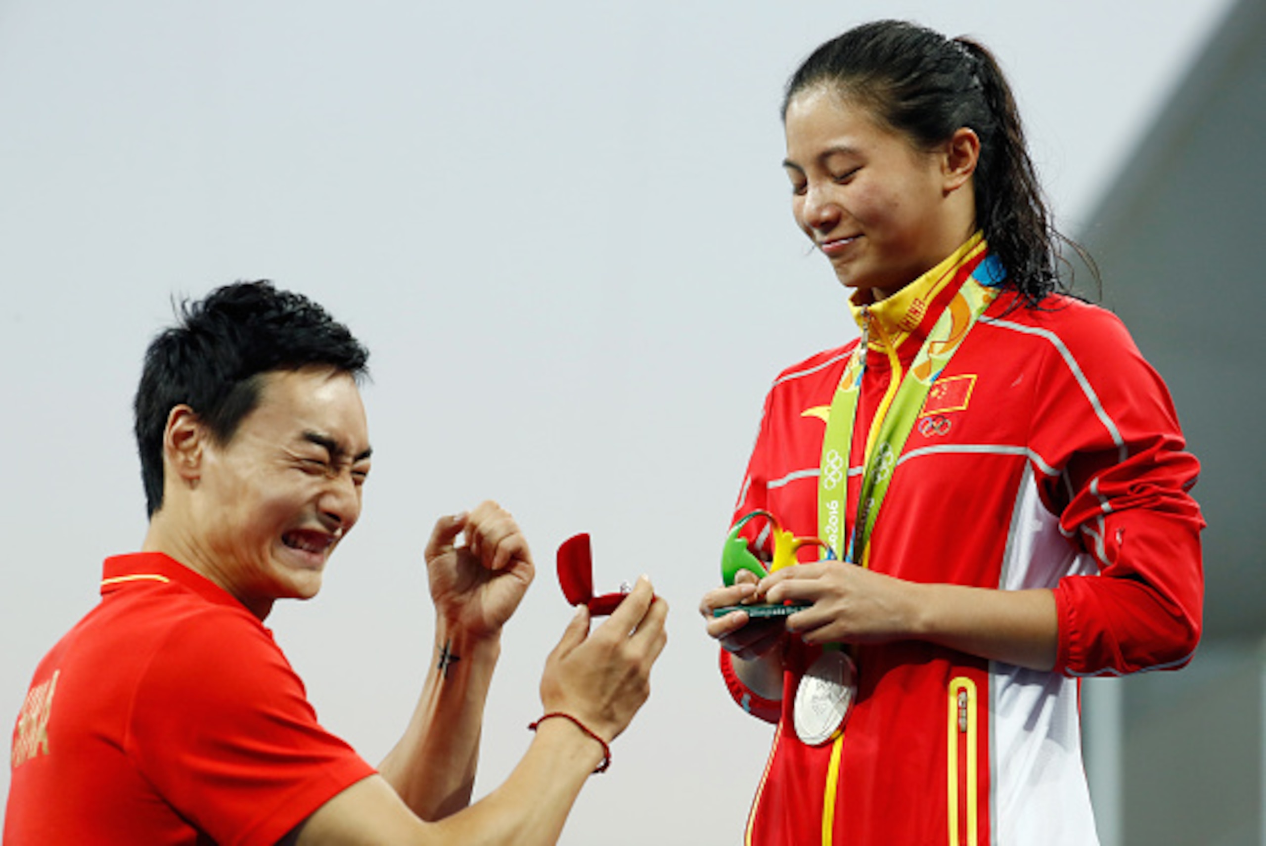 RIO DE JANEIRO, BRAZIL - AUGUST 14:  Chinese diver Qin Kai proposes to silver medalist He Zi of China on the podium during the medal ceremony for the Women's Diving 3m Springboard Final on Day 9 of the Rio 2016 Olympic Games at Maria Lenk Aquatics Centre 