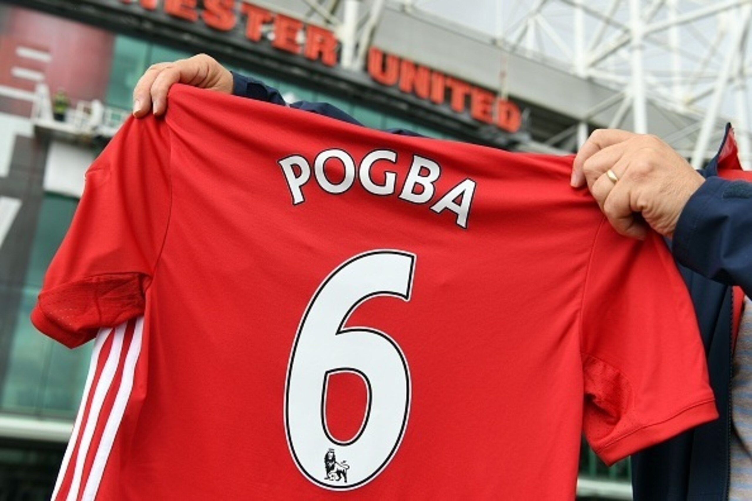 A man poses for pictures after purchasing a Manchester United shirt with the name and squad number of recent signing French midfielder Paul Pogba outside Old Traford in Manchester, north west England, on August 9, 2016.
The world record for a transfer fee