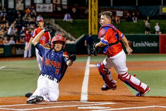 ABERDEEN, MD - AUGUST 05: Kairi Matsumura #17 of Japan scores as Yandel Lopez #8 of Puerto Rico is unable to make the catch in the International Championship game between Japan and Puerto Rico during the Cal Ripken World Series at The Ripken Experience Po