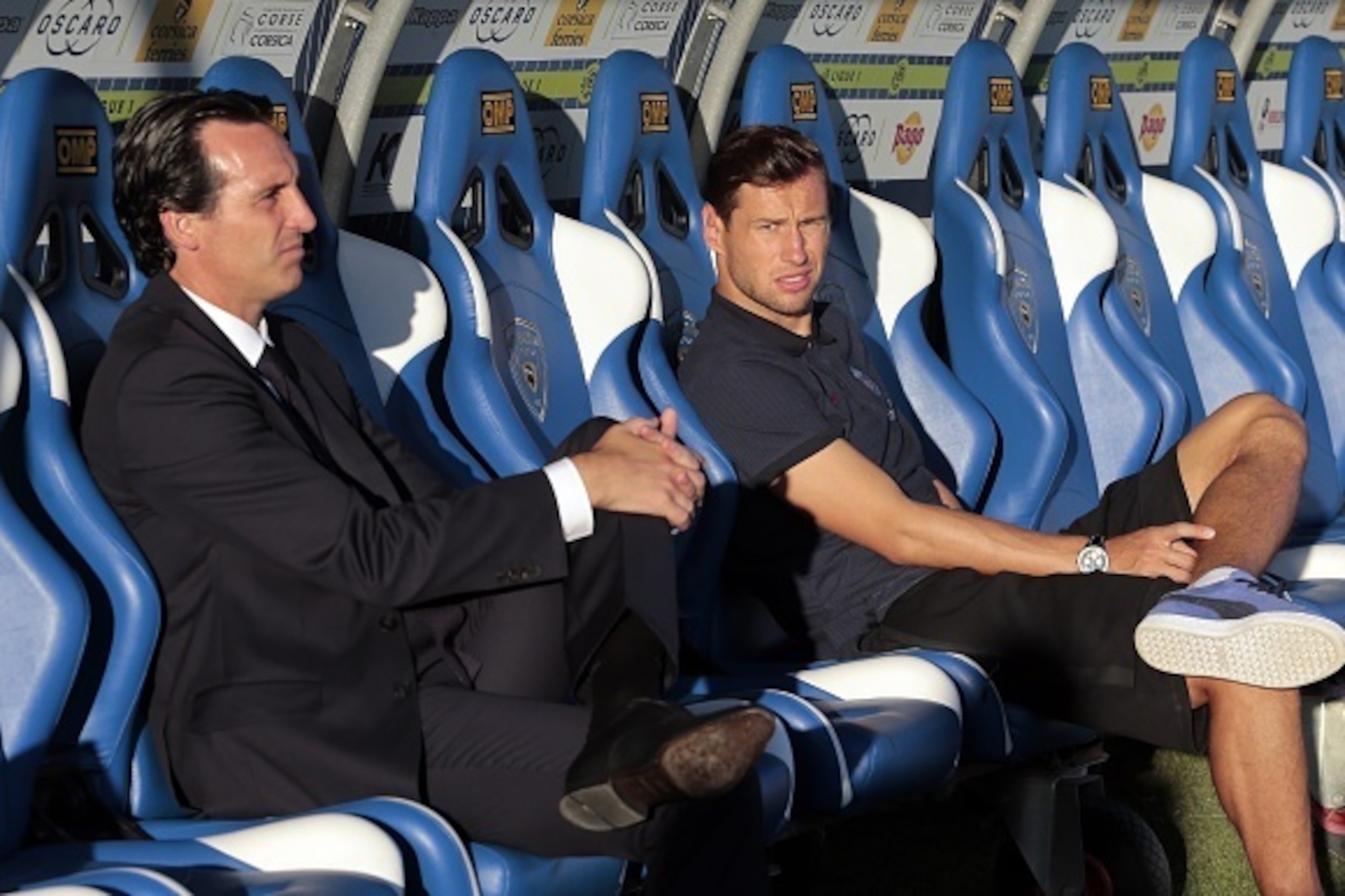 Paris Saint-Germain's Spanish head coach Unai Emery (L) and Paris Saint-Germain's Polish defender Grzegorz Krychowiak sit on the stands prior to the French Ligue 1 football match between  Bastia (SCB) and Paris Saint Germain (PSG) on August 12, 2016 at th