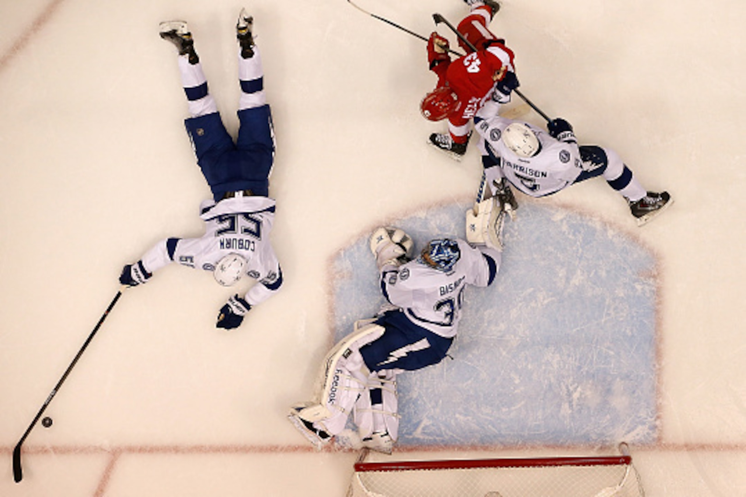 DETROIT, MI - APRIL 27:  Braydon Coburn #55 of the Tampa Bay Lightning dives for the puck next to teammates Ben Bishop #30 and Jason Garrison #5 along with Darren Helm #43 of the Detroit Red Wings in Game Six of the Eastern Conference Quarterfinals during