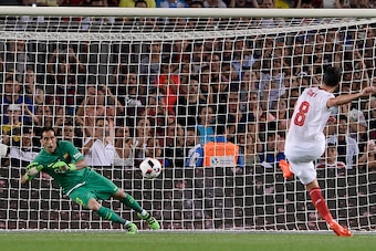 Barcelona's Chilean goalkeeper Claudio Bravo (L) stops a ball from a  penalty kick by Sevilla's midfielder Vicente Iborra during the second leg of the Spanish Supercup football match between FC Barcelona and Sevilla FC at the Camp Nou stadium in Barcelona