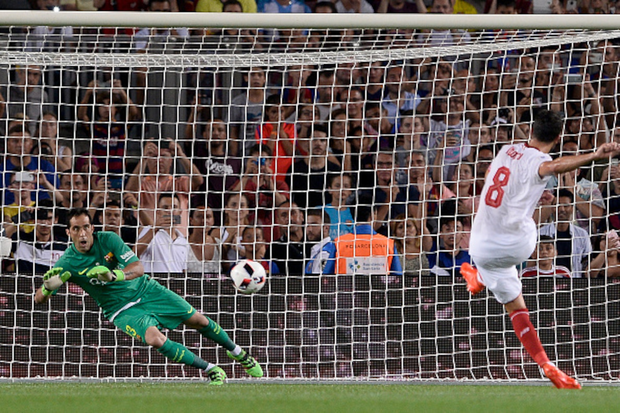 Barcelona's Chilean goalkeeper Claudio Bravo (L) stops a ball from a  penalty kick by Sevilla's midfielder Vicente Iborra during the second leg of the Spanish Supercup football match between FC Barcelona and Sevilla FC at the Camp Nou stadium in Barcelona