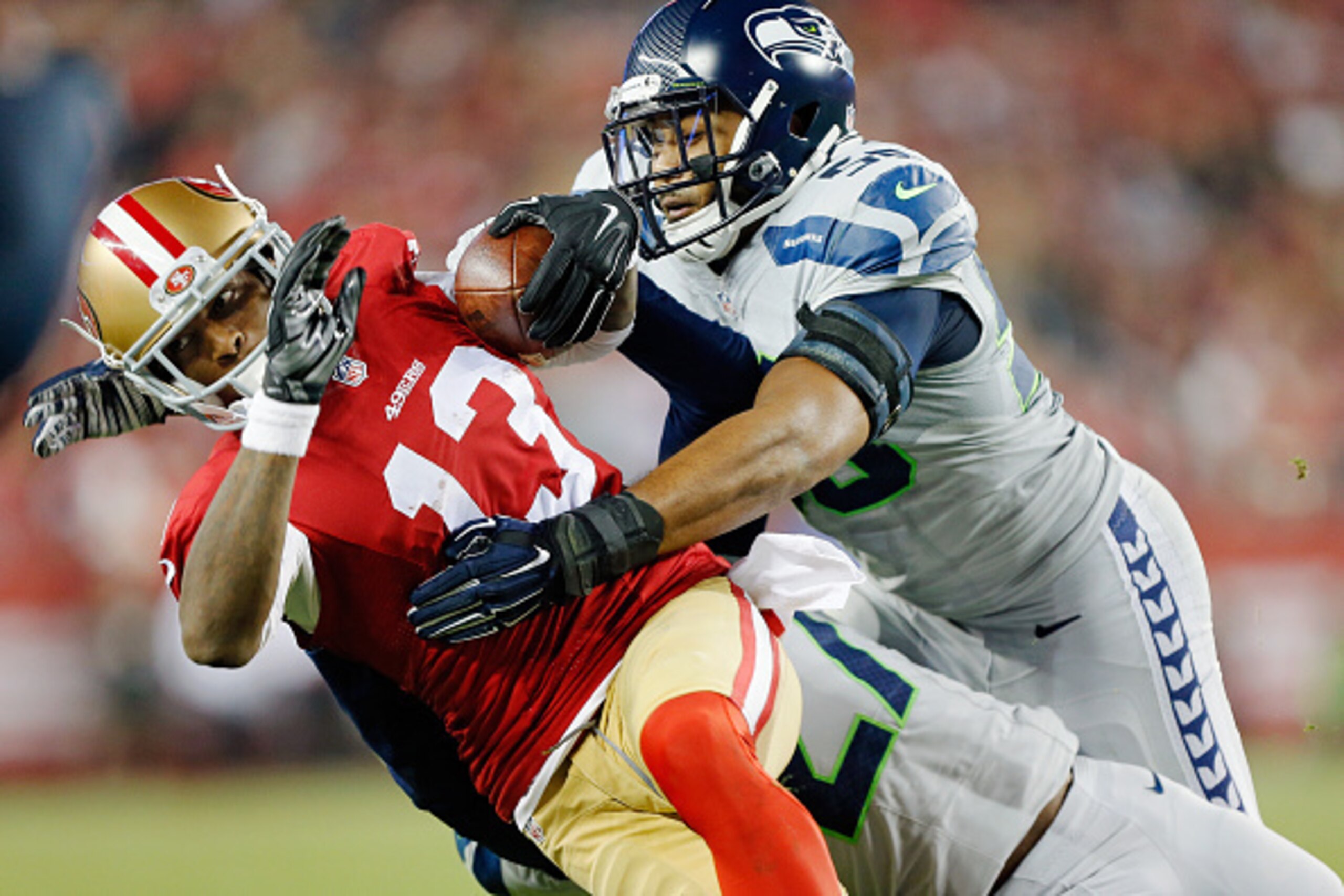 SANTA CLARA, CA - NOVEMBER 27:  Cornerback Tharold Simon #27 and linebacker K.J. Wright #50 of the Seattle Seahawks tackle wide receiver Stevie Johnson #13 of the San Francisco 49ers on an eight-yard gain in the last minute of the second quarter on Novemb