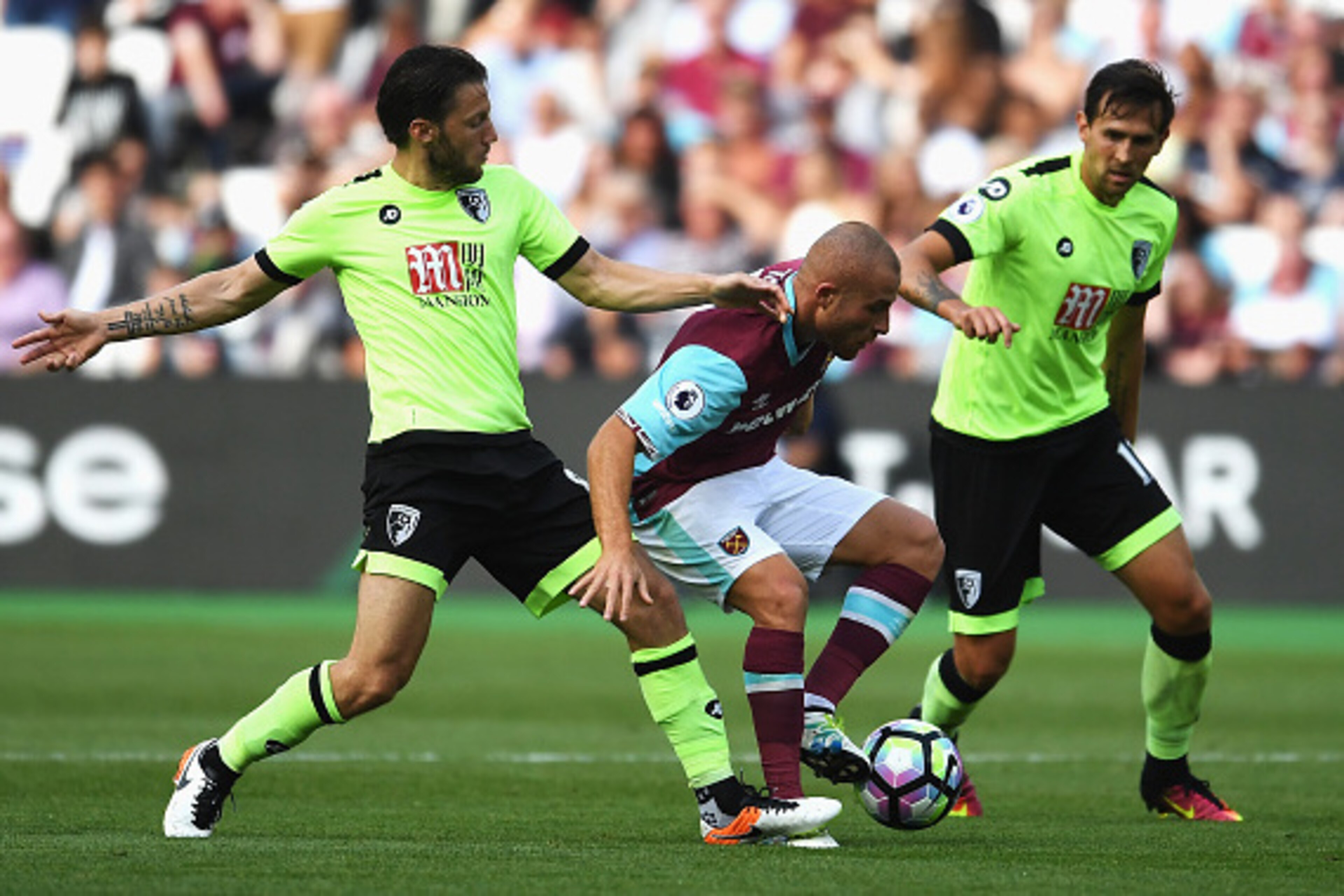 LONDON, ENGLAND - AUGUST 21: Gokhan Tore of West Ham United is tackled by Harry Arter (L) and Charlie Daniels of AFC Bournemouth during the Premier League match between West Ham United and AFC Bournemouth at London Stadium on August 21, 2016 in London, En