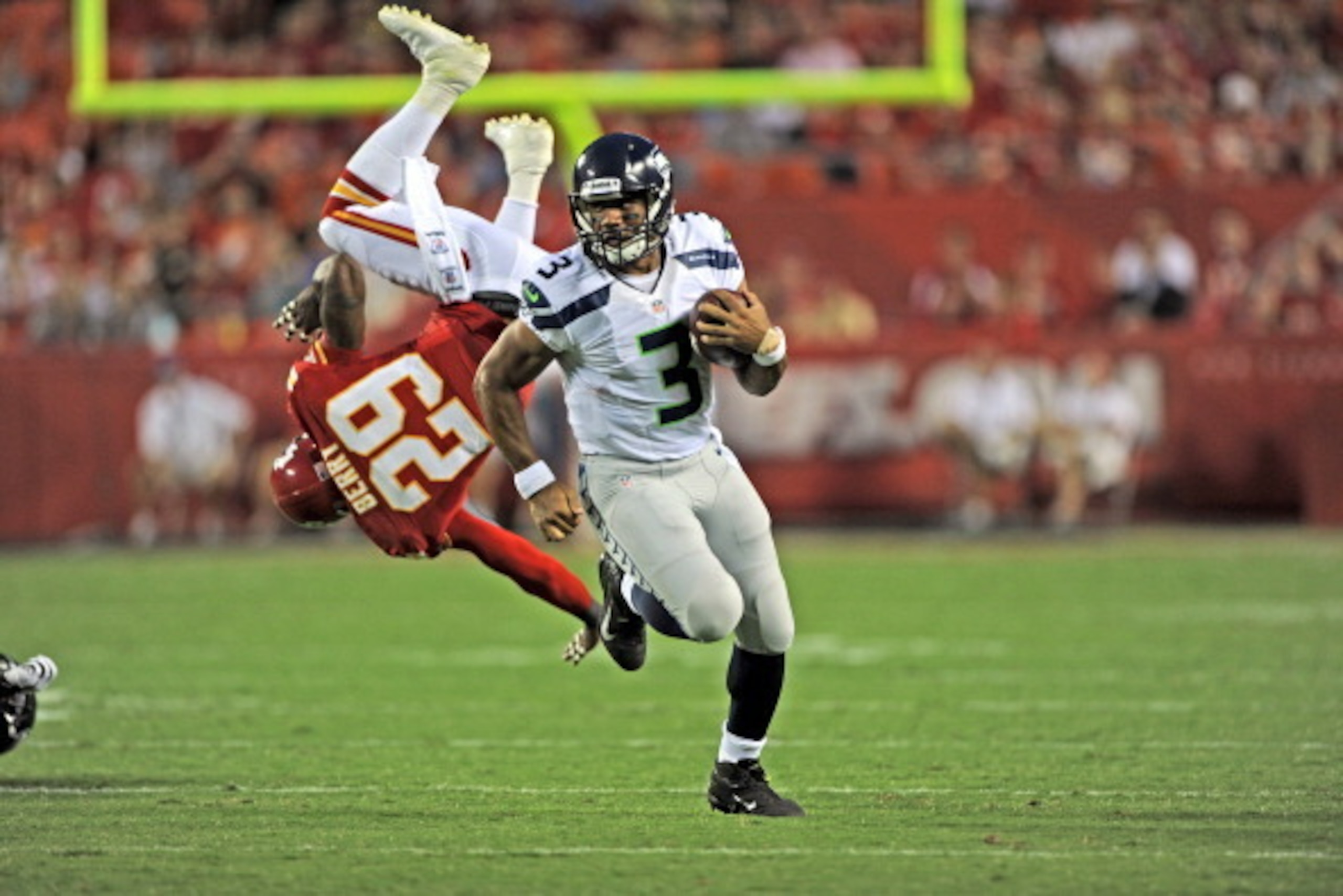 KANSAS CITY, MO - AUGUST 24:  Quarterback Russell Wilson #3 of the Seattle Seahawks rushes around the end for a first down, as safety Eric Berry #29 of the Kansas City Chiefs gets blocked into the air during the first half of a preseason game on August 24