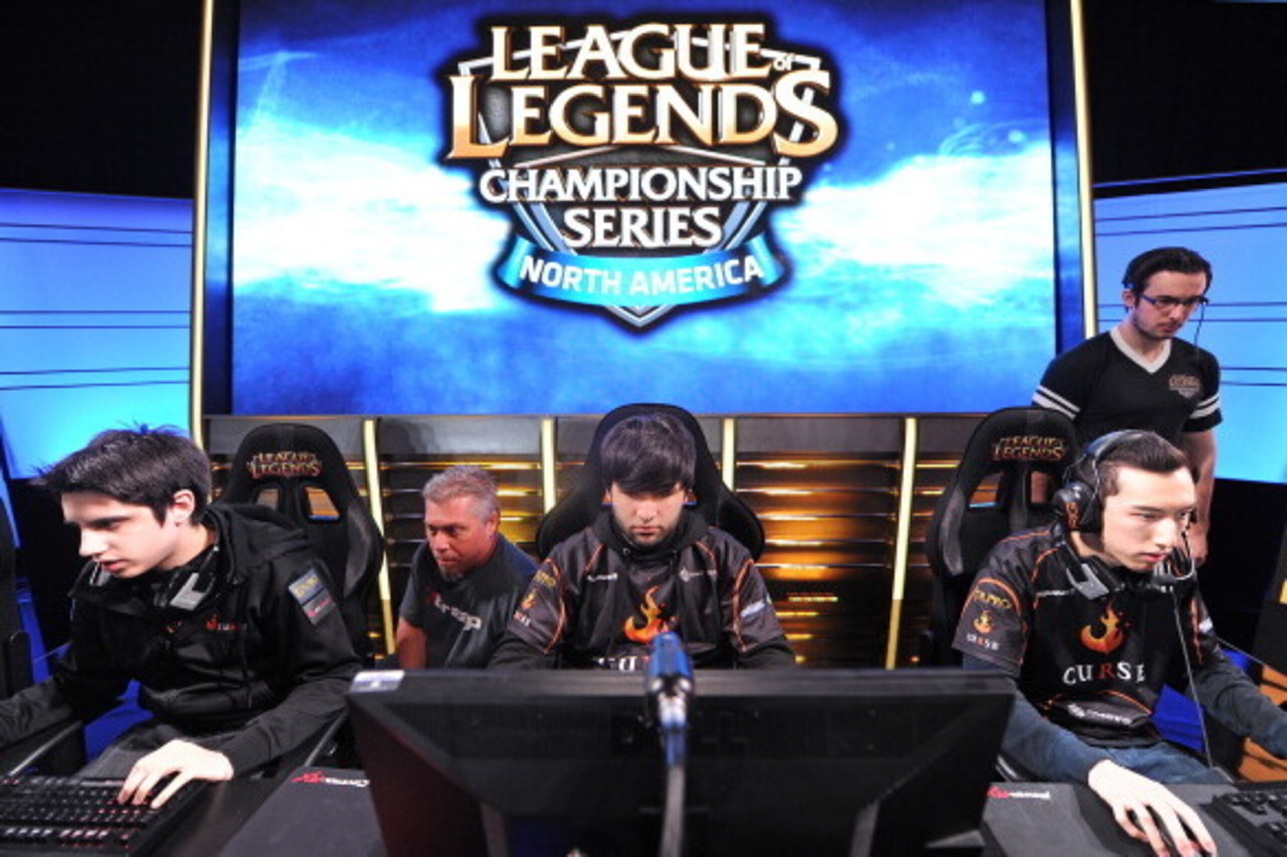 Team Curse players Christian 'IWillDominate' Rivera (L), Joedat 'Voyboy' Esfahani (C) and David 'Cop' Roberson (R) prepare for the start of a match as two broadcast technicians (background) prepare the live video feed, during the League of Legends North Team Curse players Christian 'IWillDominate' Rivera (L), Joedat 'Voyboy' Esfahani (C) and David 'Cop' Roberson (R) prepare for the start of a match as two broadcast technicians (background) prepare the live video feed, during the League of Legends North