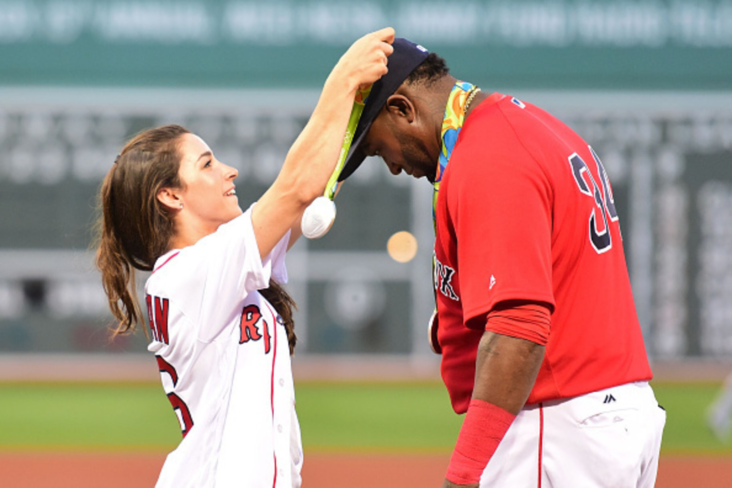 BOSTON, MA - AUGUST 26:  Olympic gymnast Aly Raisman puts a medal on David Ortiz #34 of the Boston Red Sox before throwing out a ceremonial first pitch before a game against the Kansas City Royals on August 26, 2016 at Fenway Park in Boston, Massachusetts