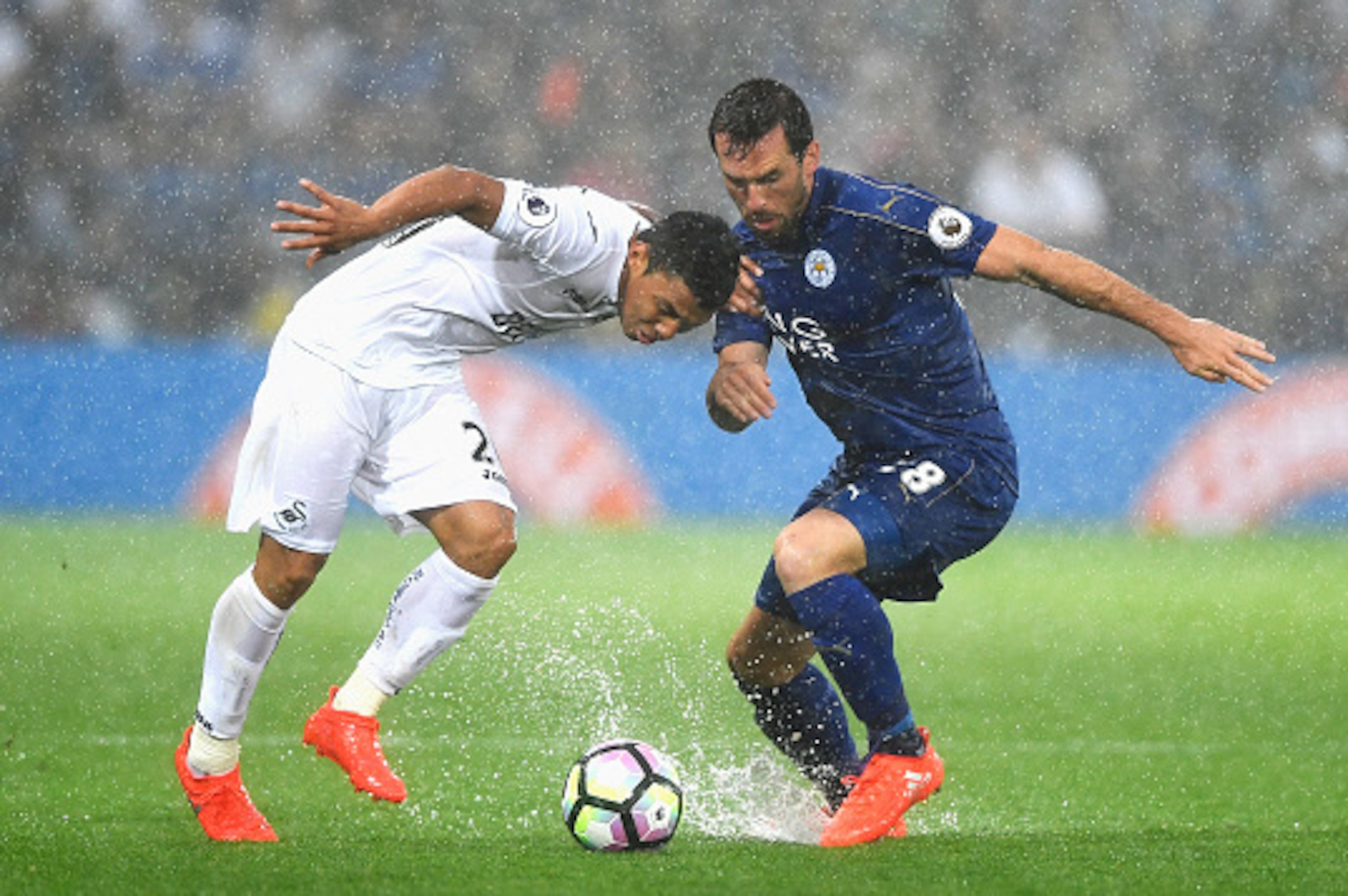 LEICESTER, ENGLAND - AUGUST 27: Jefferson Montero of Swansea City (L) attempts to take the ball past Christian Fuchs of Leicester City (R) during the Premier League match between Leicester City and Swansea City at The King Power Stadium on August 27, 2016
