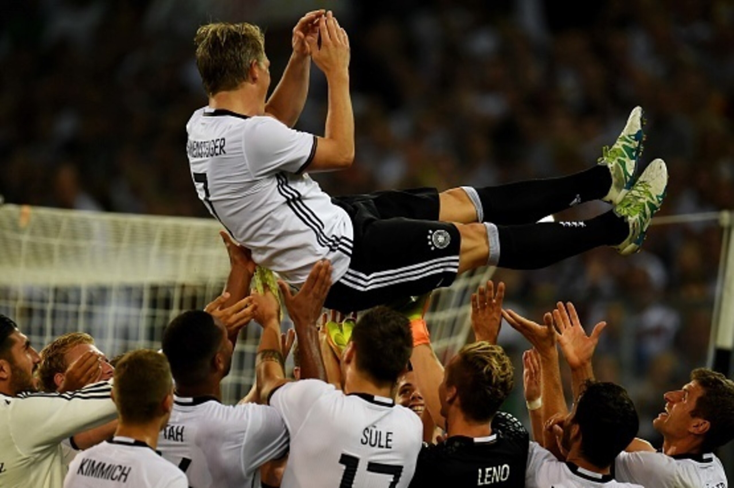 TOPSHOT - Germany's midfielder Bastian Schweinsteiger is thrown in the air by his team-mates after the football friendly match between Germany and Finland, his last game for his country, in Monchengladbach, western Germany on on August 31, 2016.
 / AFP / 