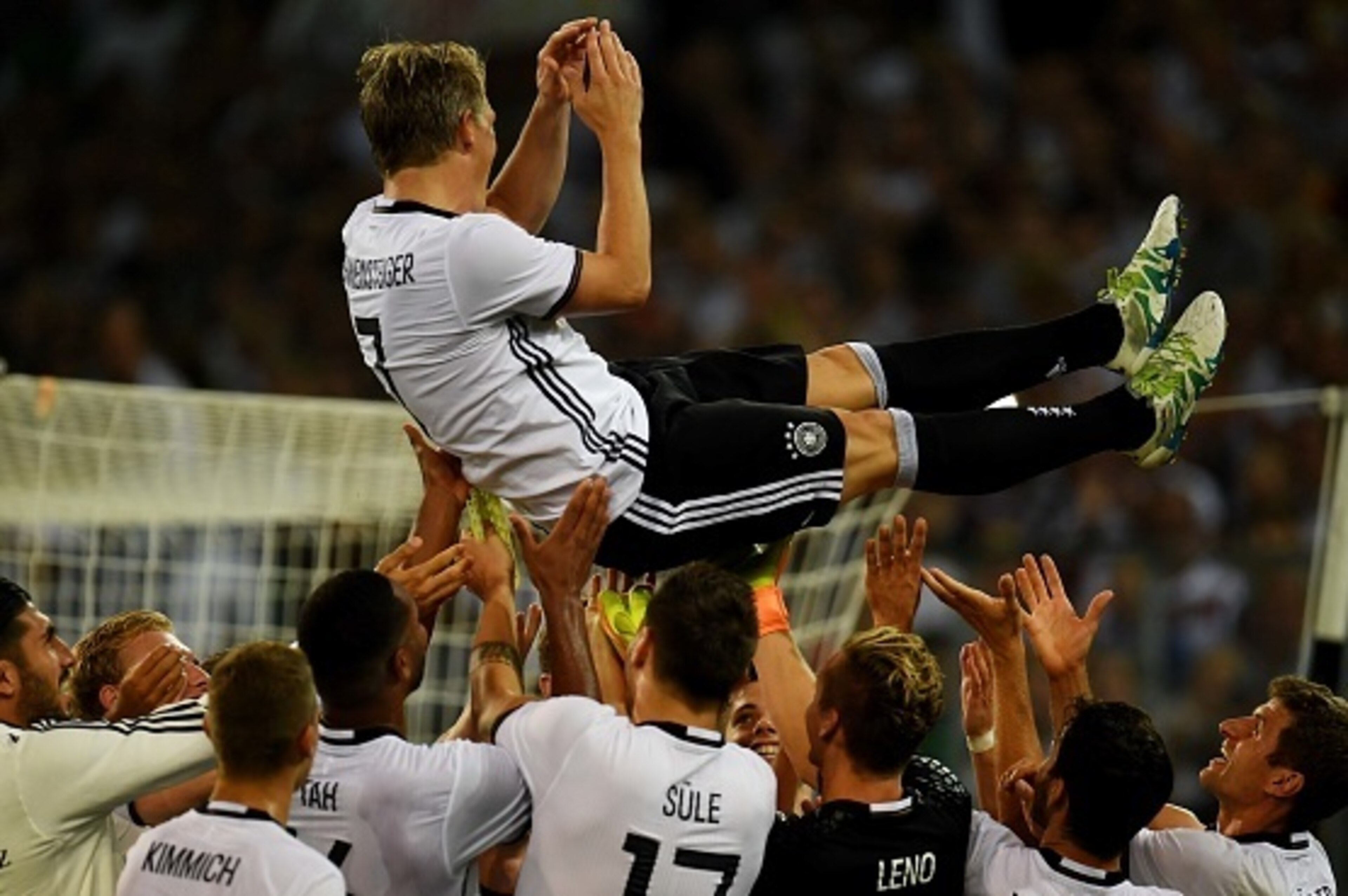 TOPSHOT - Germany's midfielder Bastian Schweinsteiger is thrown in the air by his team-mates after the football friendly match between Germany and Finland, his last game for his country, in Monchengladbach, western Germany on on August 31, 2016.
 / AFP / 