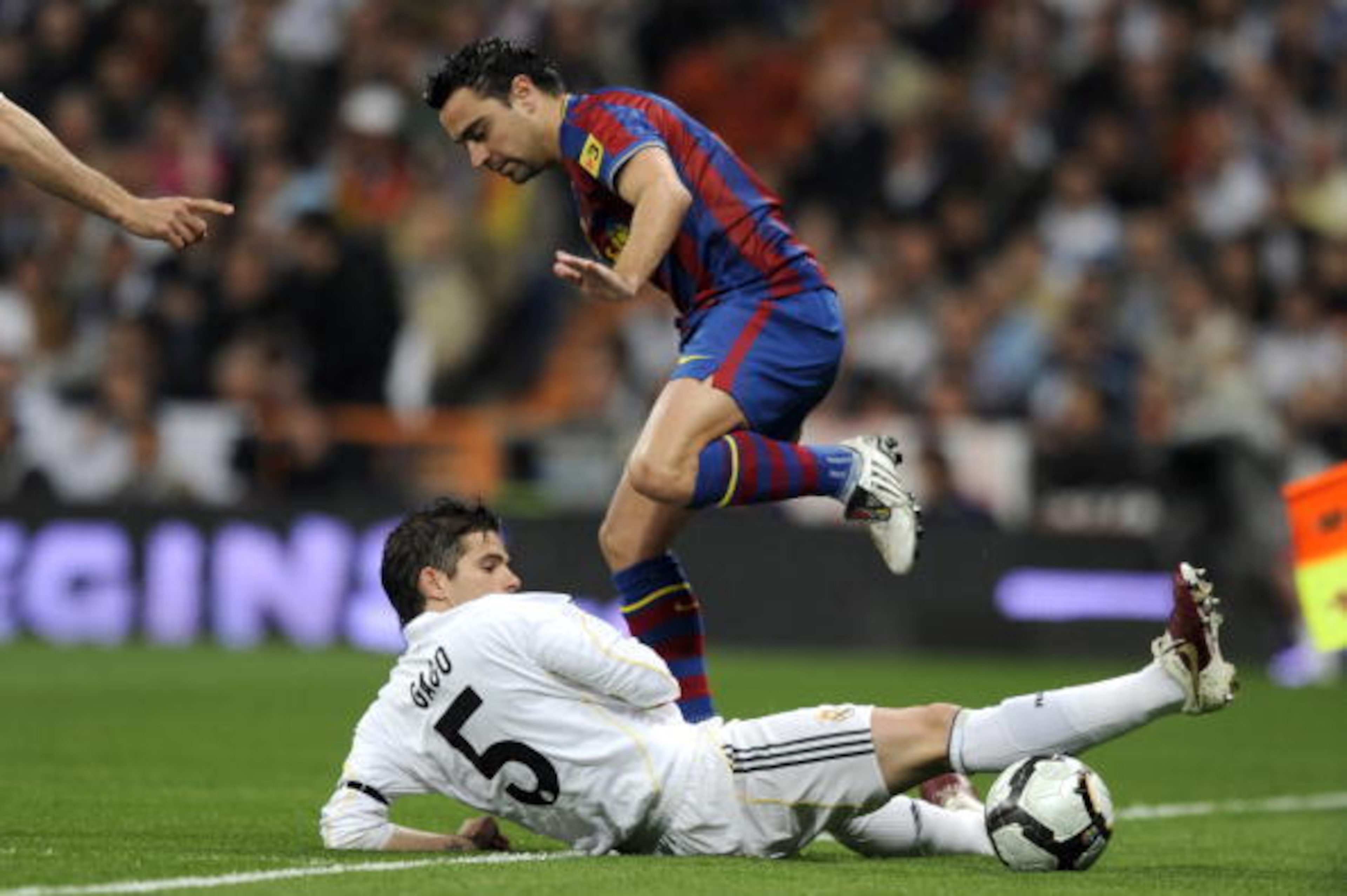 Real Madrid's Fernando Gago (down) vies for the ball with Barcelona's midfielder Xavi Hernandez during the 'El Clasico' Spanish League football match Real Madrid against Barcelona at the Santiago Bernabeu stadium in Madrid, on April 10, 2010. AFP PHOTO/Da