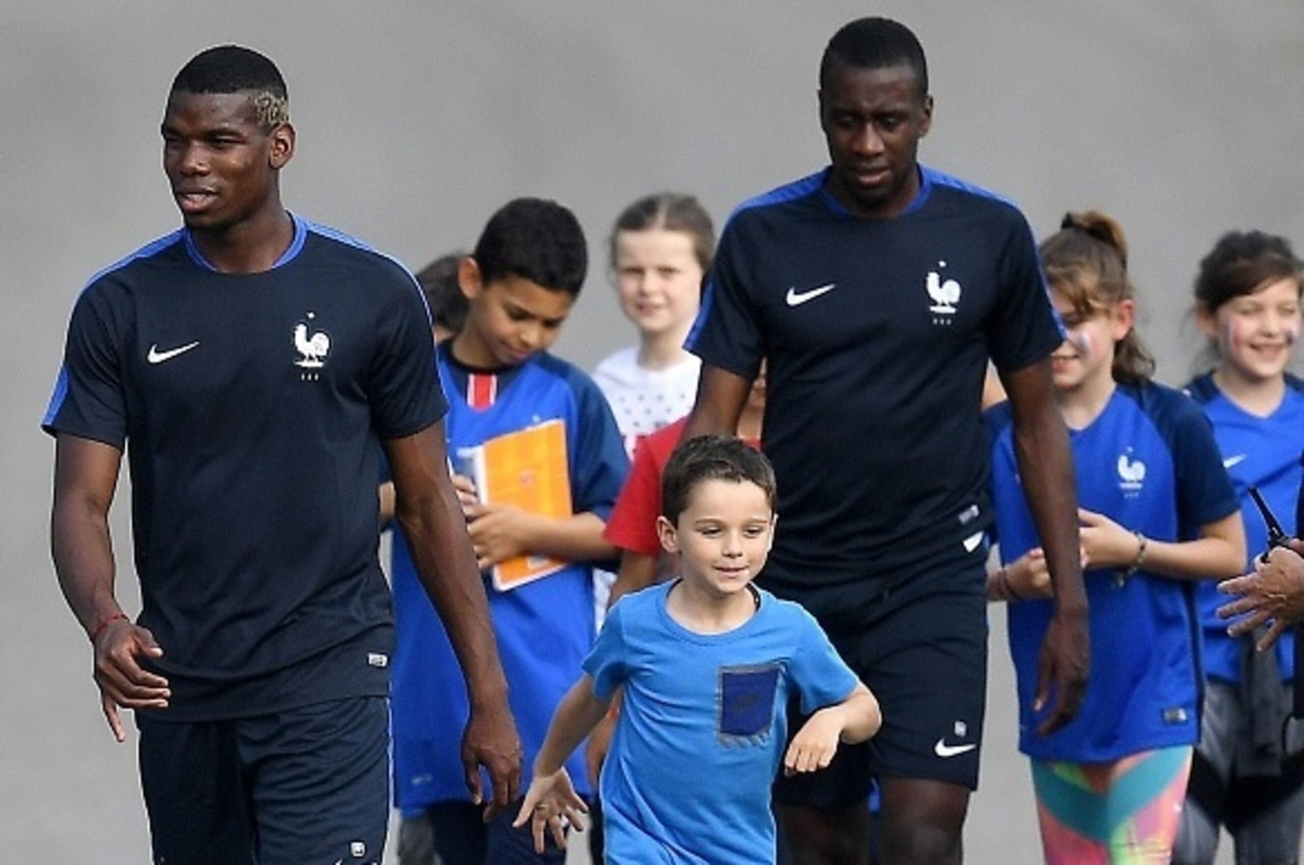France's midfielder Paul Pogba (L) and France's midfielder Blaise Matuidi are accompanied by children as they arrive for a training session in Clairefontaine en Yvelines on June 6, 2016, four days ahead of the beginning of the Euro 2016 European football 
