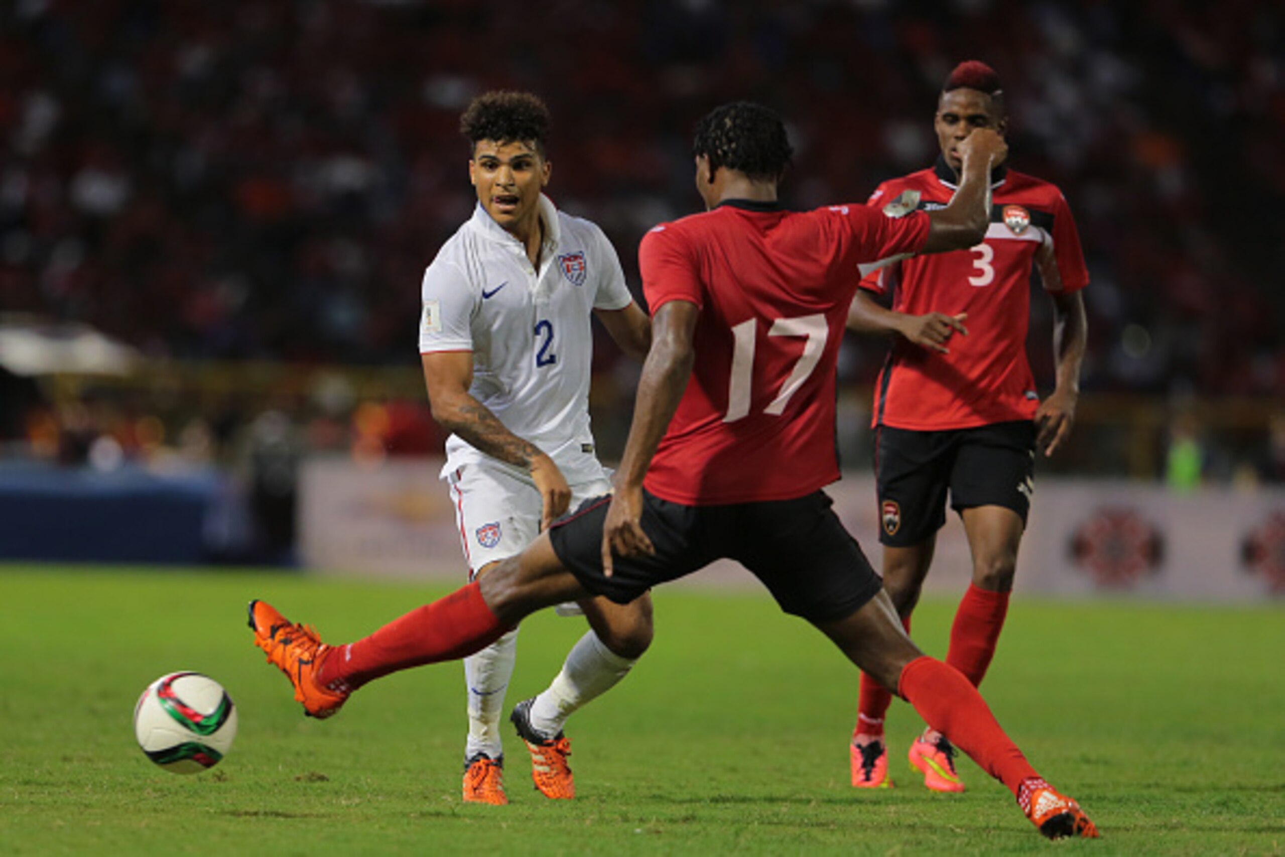 PORT OF SPAIN, TRINIDAD & TOBAGO - NOVEMBER 17: USA's DeAndre Yedlin #2 passes the ball past T&T's Mekeil Williams #17 as Williams team mate Joevin Jones #3 looks on during a World Cup Qualifier between Trinidad and Tobago and USA as part of the FIFA Worl