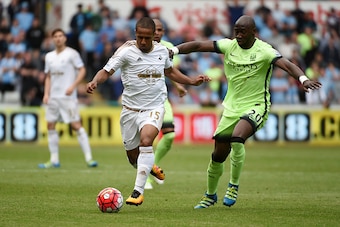 SWANSEA, WALES - MAY 15: Wayne Routledge of Swansea City and Eliaquim Mangala of Manchester City compete for the ball during the Barclays Premier League match between Swansea City and Manchester City at the Liberty Stadium on May 15, 2016 in Swansea, Wale