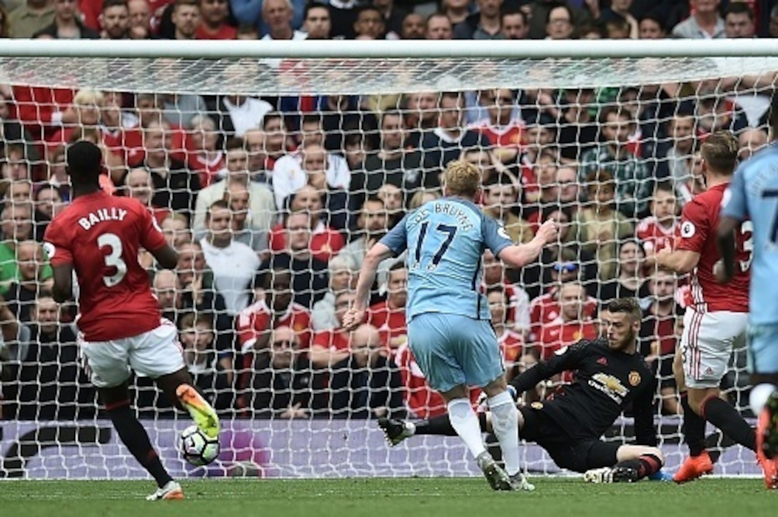 Manchester City's Belgian midfielder Kevin De Bruyne (2nd L) scores the opening goal past Manchester United's Spanish goalkeeper David de Gea (3rd L) during the English Premier League football match between Manchester United and Manchester City at Old Tra