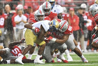 COLUMBUS, OH - SEPTEMBER 10:  D'Angelo Brewer #4 of the Tulsa Hurricane is wrapped up for no gain by Michael Hill #77 of the Ohio State Buckeyes and Dre'Mont Jones #86 of the Ohio State Buckeyes in the third quarterat Ohio Stadium on September 10, 2016 in