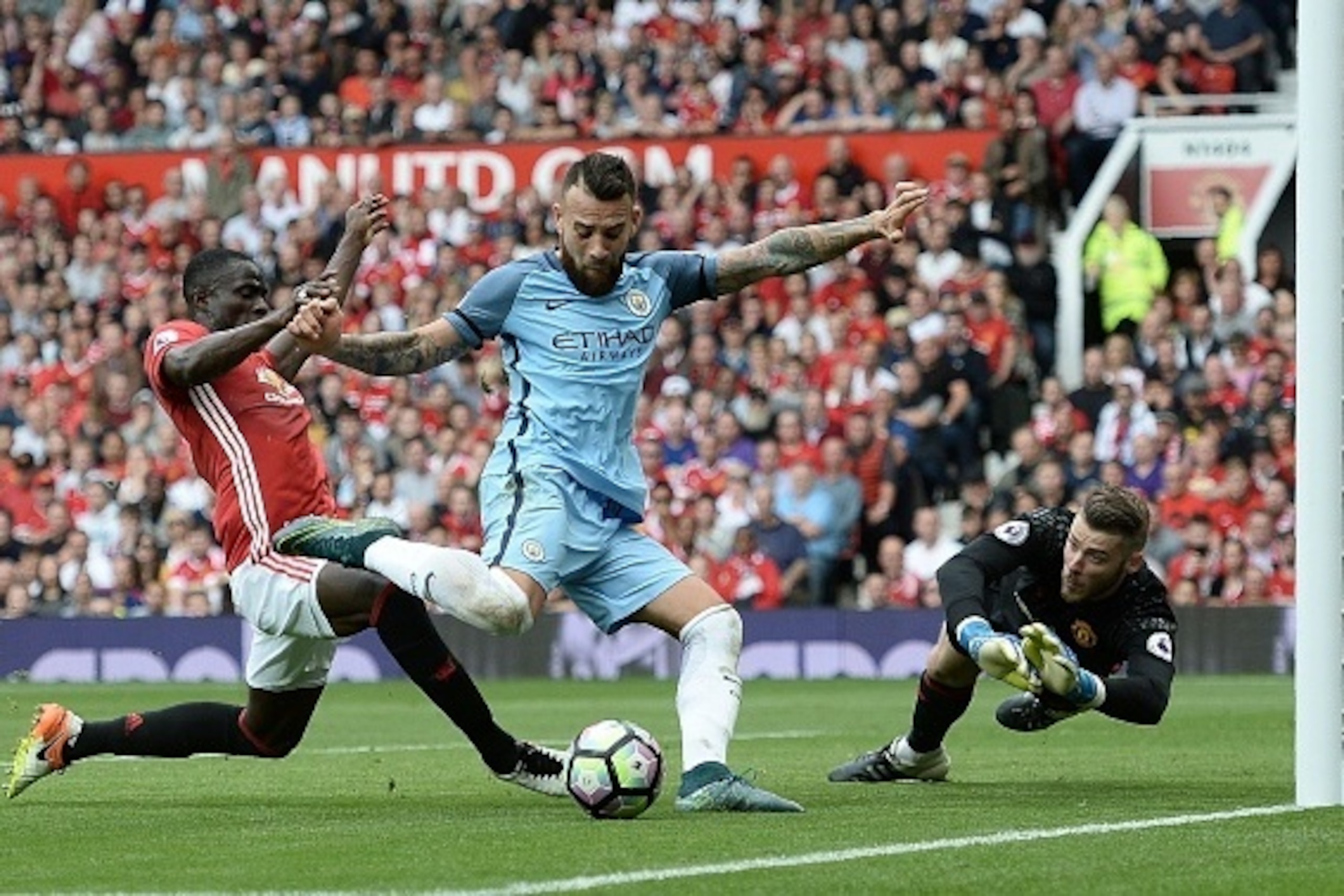 Manchester City's Argentinian defender Nicolas Otamendi (C) attempts to shoot as Manchester United's Ivorian defender Eric Bailly (L) defends and Manchester United's Spanish goalkeeper David de Gea (R) dives during the English Premier League football matc