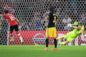 Atletico Madrid's Slovenian goalkeeper Jan Oblak (R) stops a penalty from PSV Eindhoven's Mexican midfielder Andres Guardado (L) during the UEFA Champions League football match between PSV Eindhoven and Atletico Madrid at Philips Stadium on September 13, 