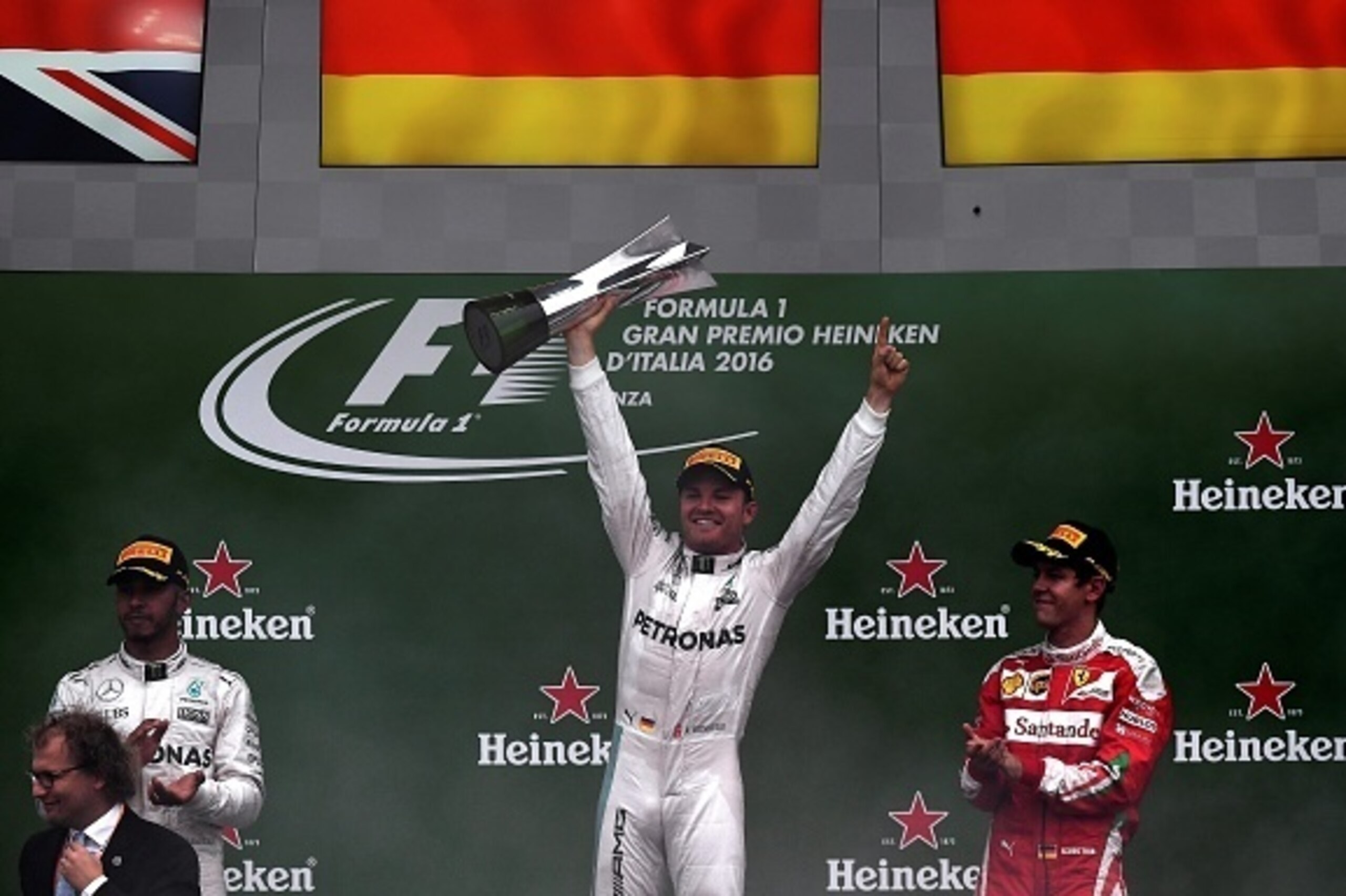 Winner Mercedes AMG Petronas F1 Team's German driver Nico Rosberg (C) celebrates on the podium holding his trophy next to second placed Mercedes AMG Petronas F1 Team's British driver Lewis Hamilton (L) and third placed Scuderia Ferrari's German driver Seb