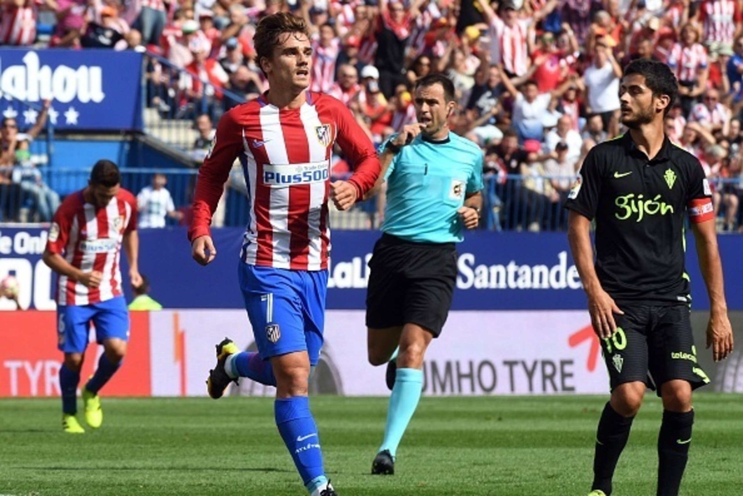 Atletico Madrid's French forward Antoine Griezmann (L) celebrates past Sporting Gijon's midfielder Nacho Cases after scoring during the Spanish league football match Club Atletico de Madrid vs Real Sporting de Gijon at the Vicente Calderon stadium in Madr