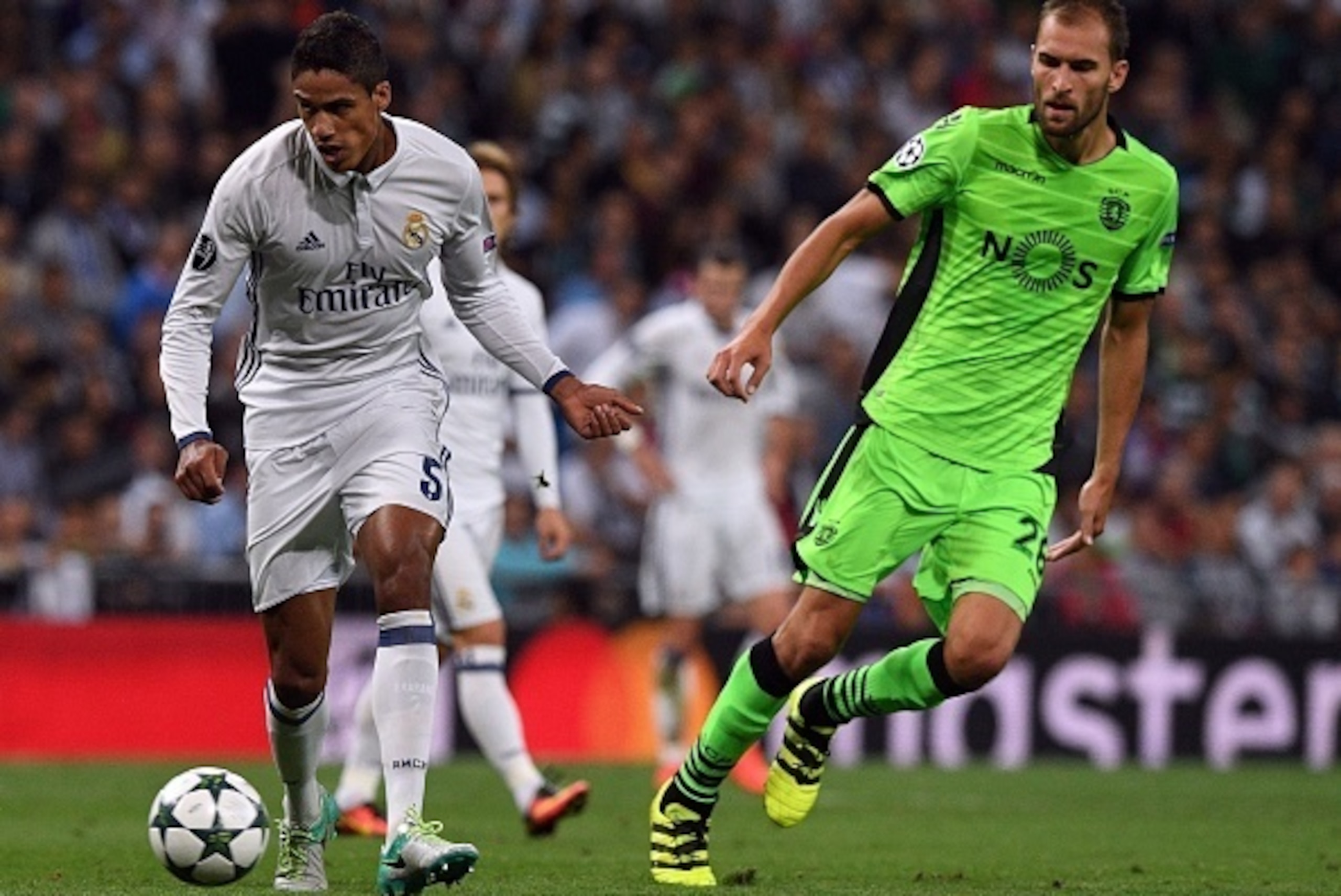 Real Madrid's French defender Raphael Varane (L) passes a ball next to Sporting's Dutch forward Bas Dost during the UEFA Champions League football match Real Madrid CF vs Sporting CP at the Santiago Bernabeu stadium in Madrid on September 14, 2016. / AFP 