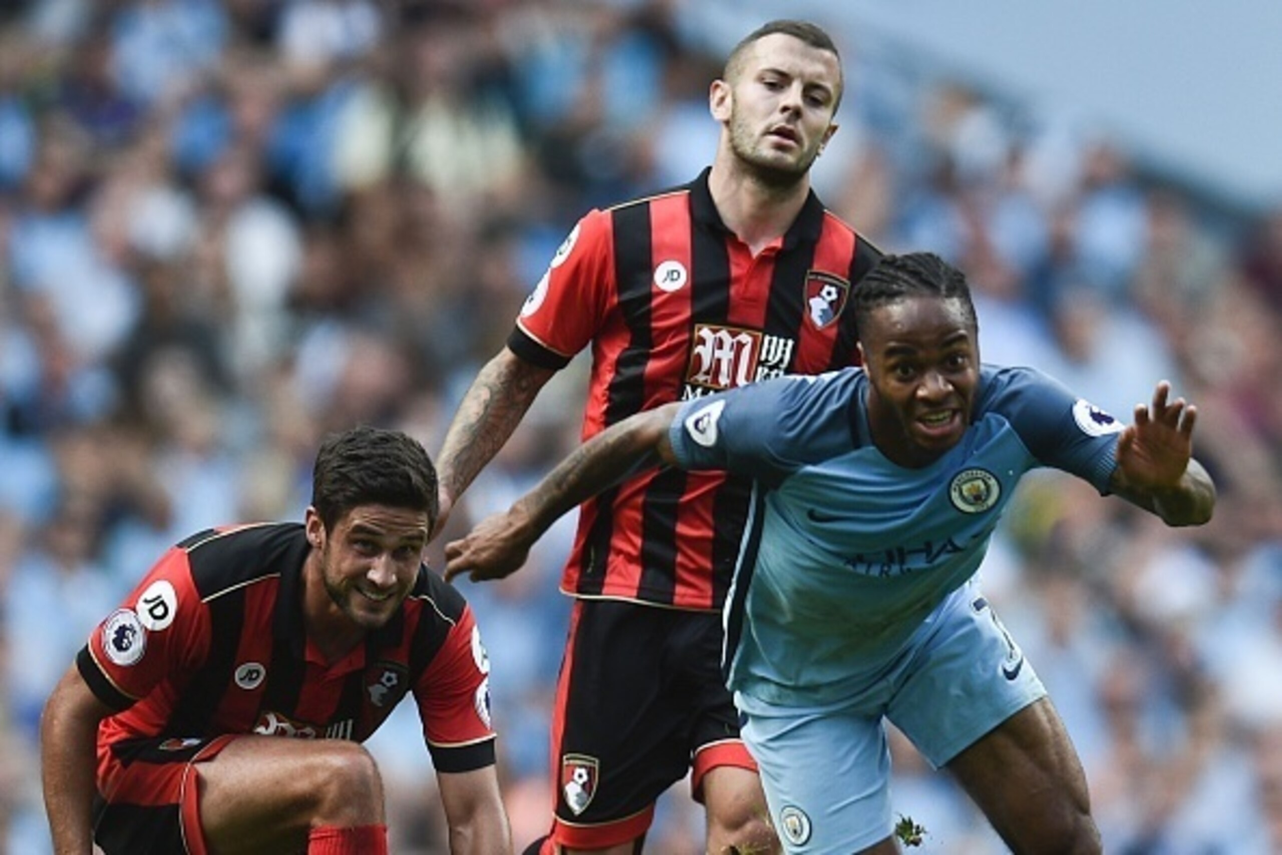 Manchester City's English midfielder Raheem Sterling (R) gets away from Bournemouth's English midfielder Jack Wilshere (C) and Bournemouth's South African-born English midfielder Andrew Surman (L) during the English Premier League football match between M