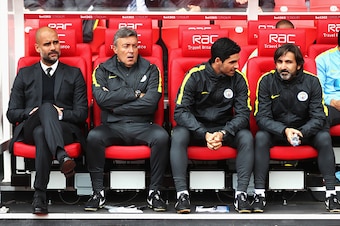 STOKE ON TRENT, ENGLAND - AUGUST 20: (L/R) Josep Guardiola, Manager of Manchester City, Domenec Torrent, Mikel Arteta and Lorenzo Buenaventura on the bench  during the Premier League match between Stoke City and Manchester City at Bet365 Stadium on August