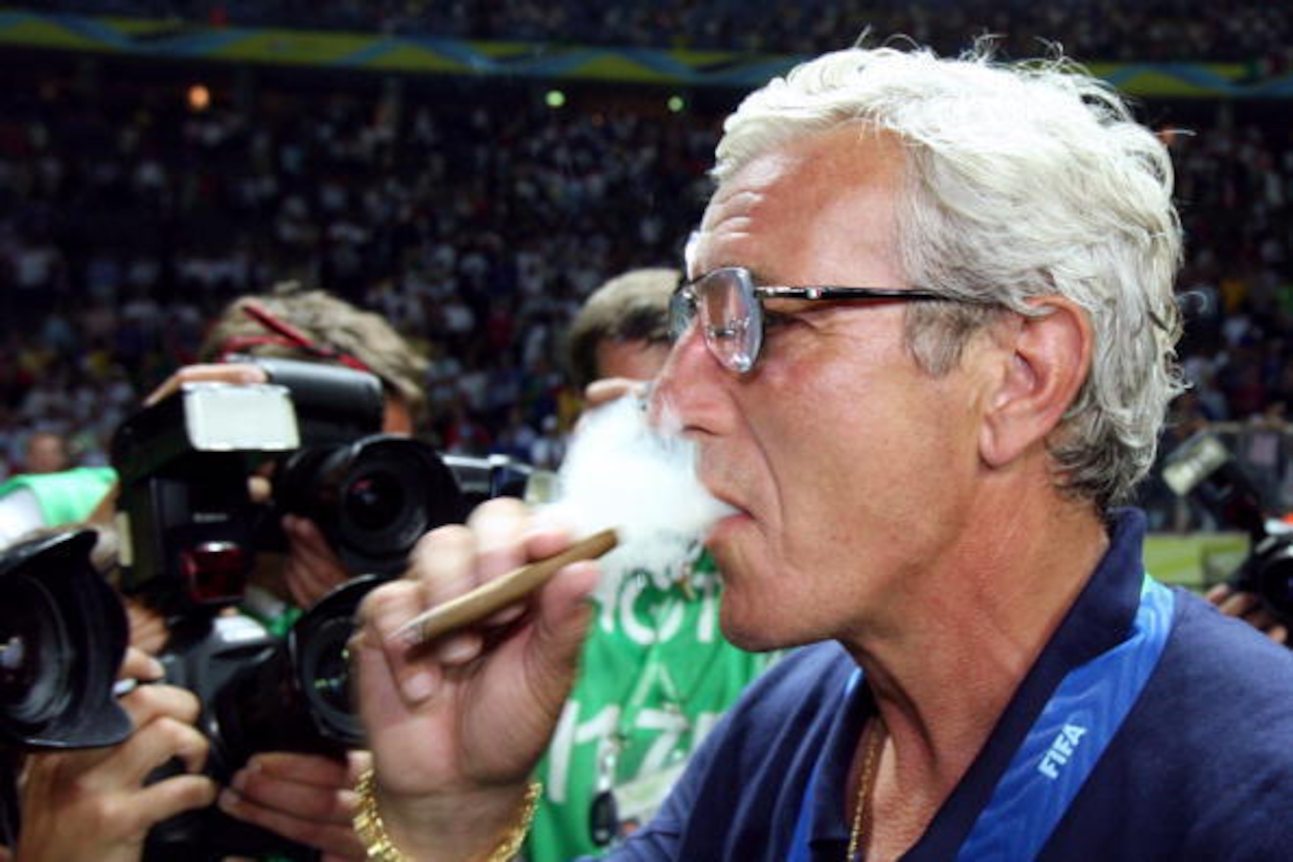 Berlin, GERMANY:  Head coach of the Italian team Marcello Lippi smokes a cigar as he celebrates Italy?s victory over France in the 2006 World Cup final football match at Berlin?s Olympic Stadium, 09 July 2006.  Italy won 5-3 on penalties.  AFP PHOTO/ ODD 