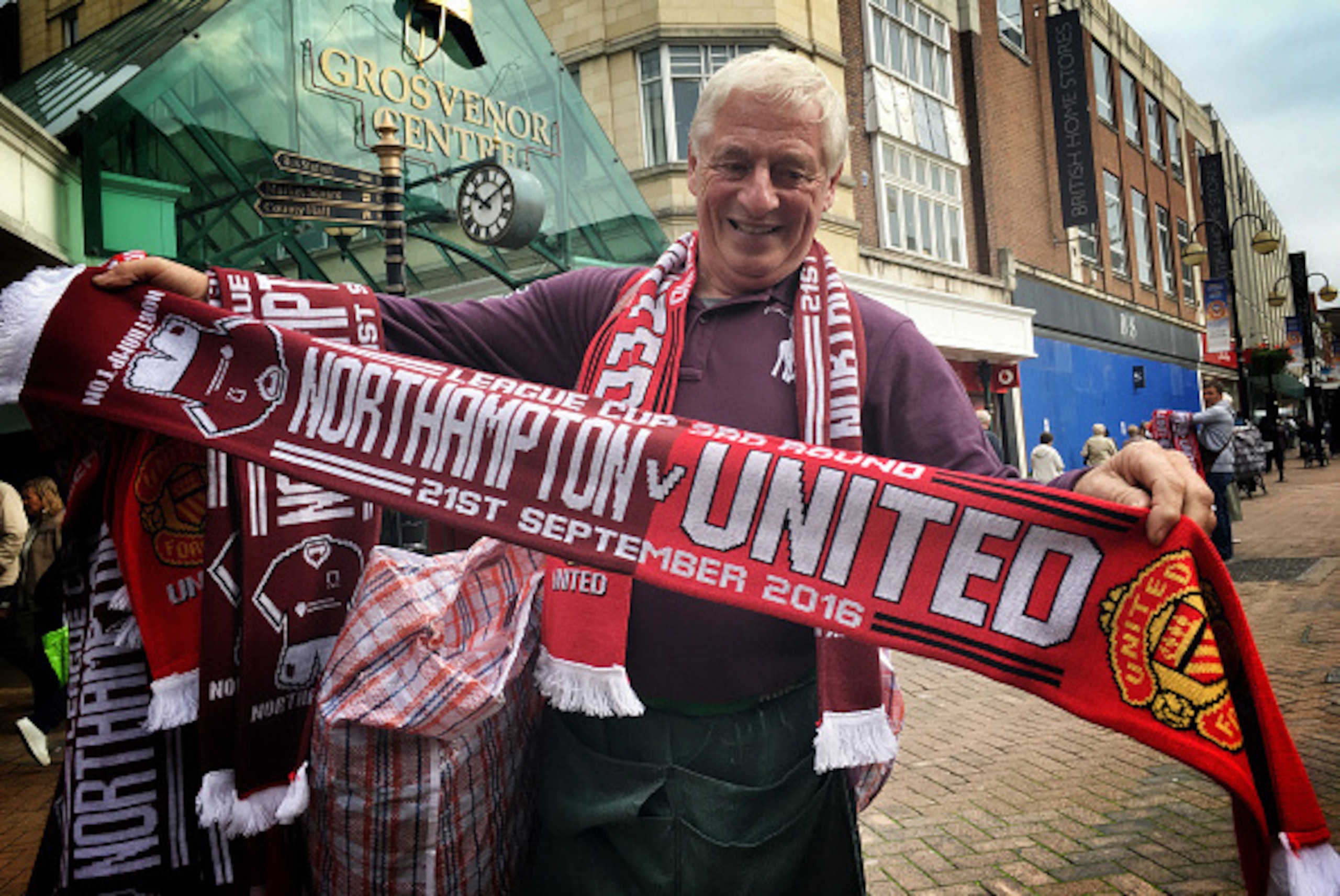 NORTHAMPTON, UNITED KINGDOM - SEPTEMBER 21:  (EDITORS NOTE: Image was processed using Snapseed) A man selling matchday scarves ahead of the EFL Cup Third Round match between Northampton Town and Manchester United poses for a photo outside the Grosvenor Ce